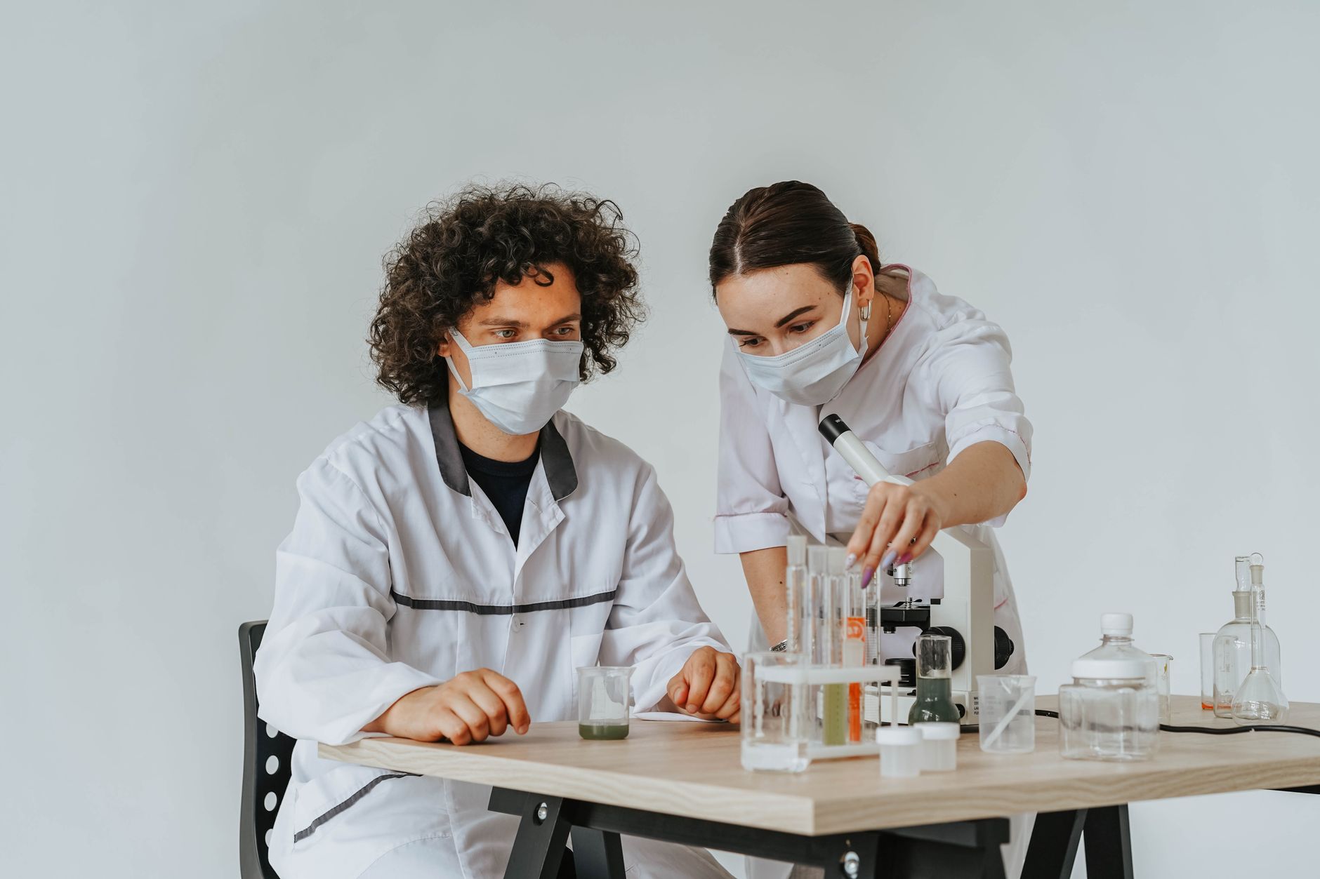 Two lab professionals studying samples with a microscope in a modern lab.