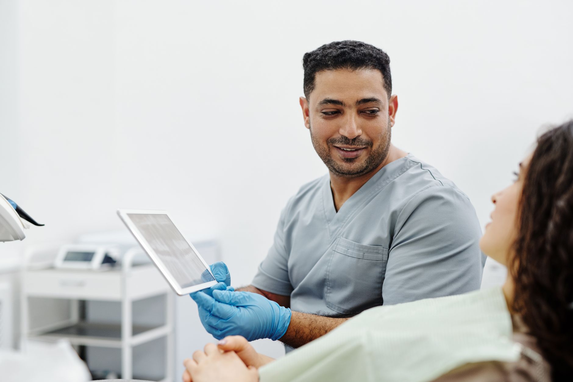 A dentist shows a patient health records on a tablet in a modern dental office.