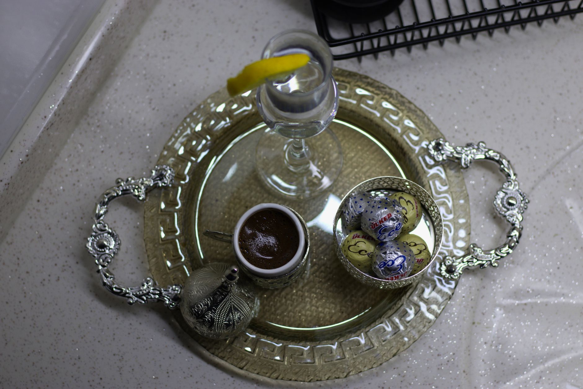 An ornate silver tray featuring Turkish coffee, sweets, and water, elegantly arranged in a clean setting.