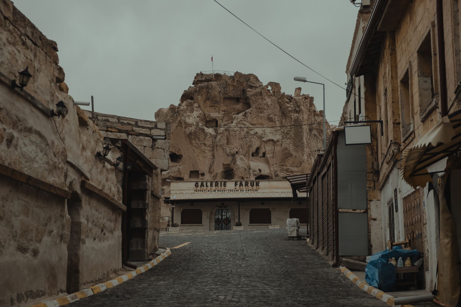 شارع مرصوف بالحجارة تصطف على جانبيه مبانٍ حجرية منحوتة في كابادوكيا.