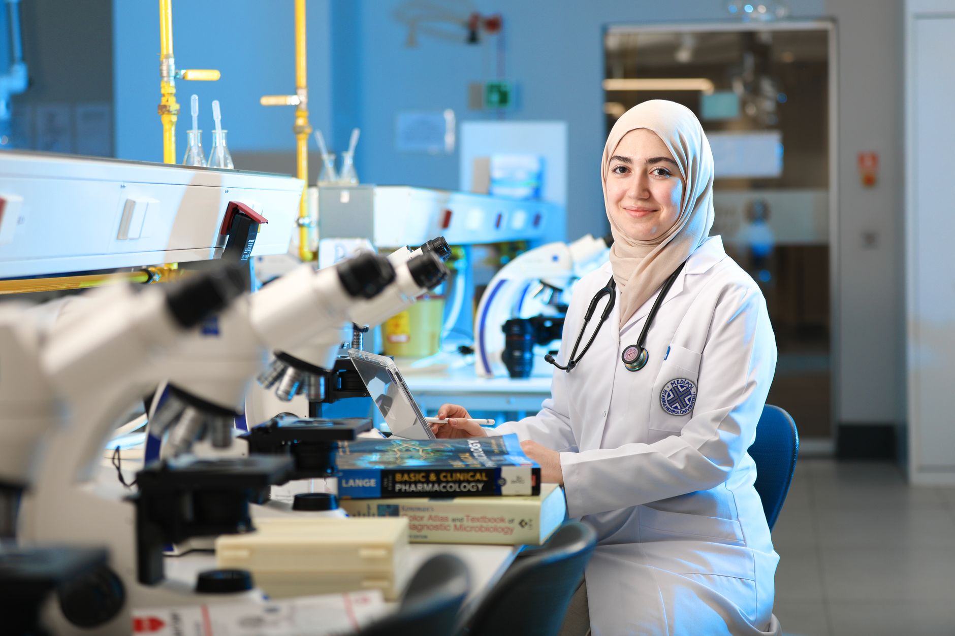 Young female researcher in a lab coat smiles at a modern medical research centre in Ankara.