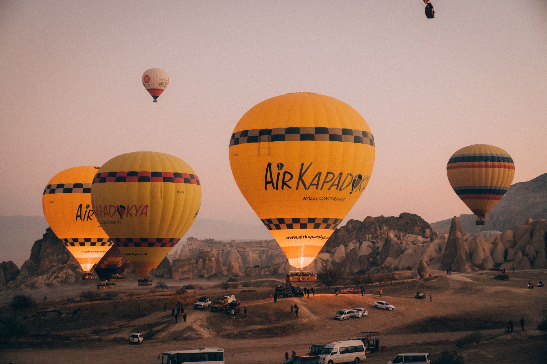 Şafak vakti Kapadokya'nın eşsiz kaya oluşumları üzerinde uçan rengarenk sıcak hava balonları.