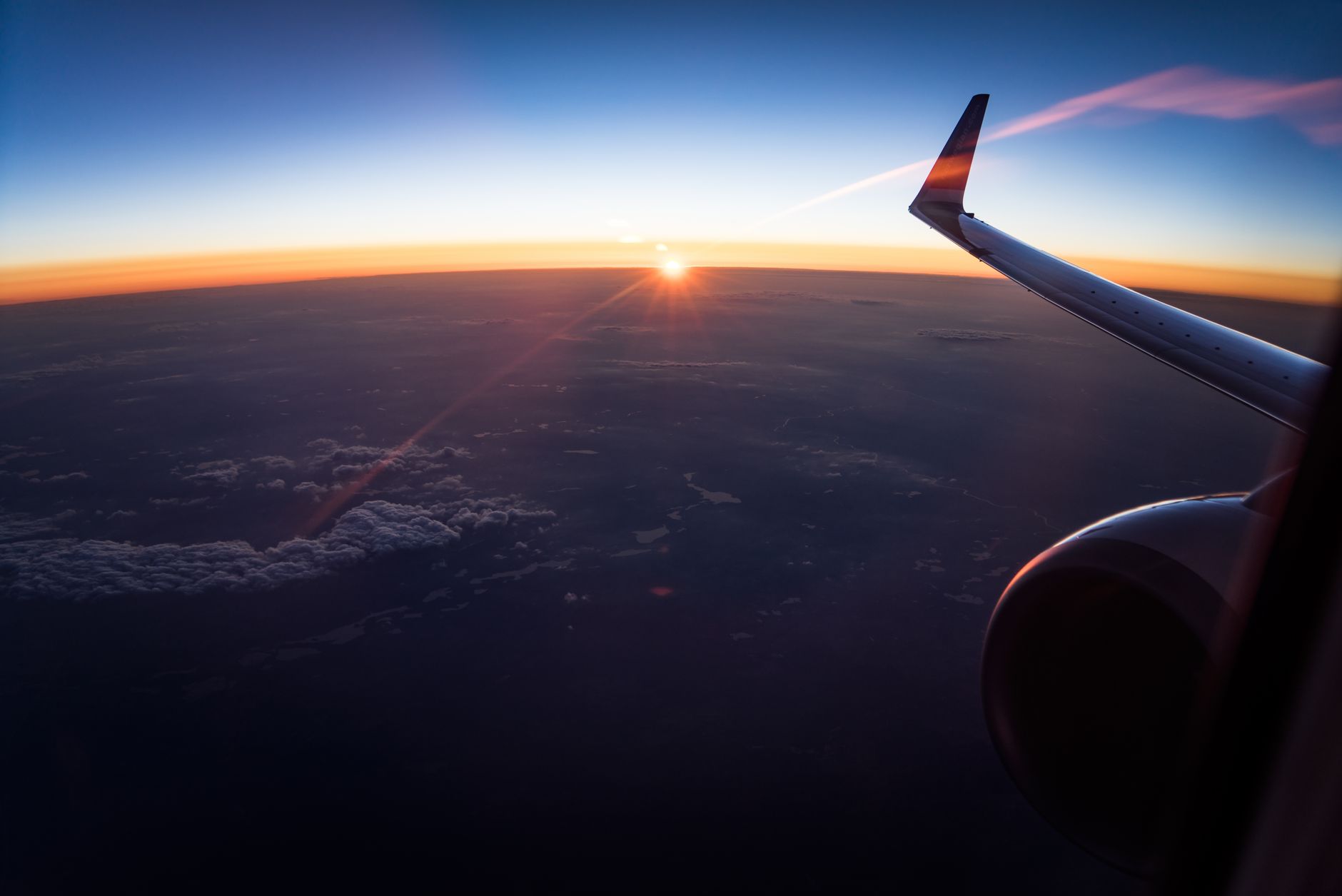 Stunning sunset view from an airplane wing, showcasing clouds and horizon during a flight to Türkiye.