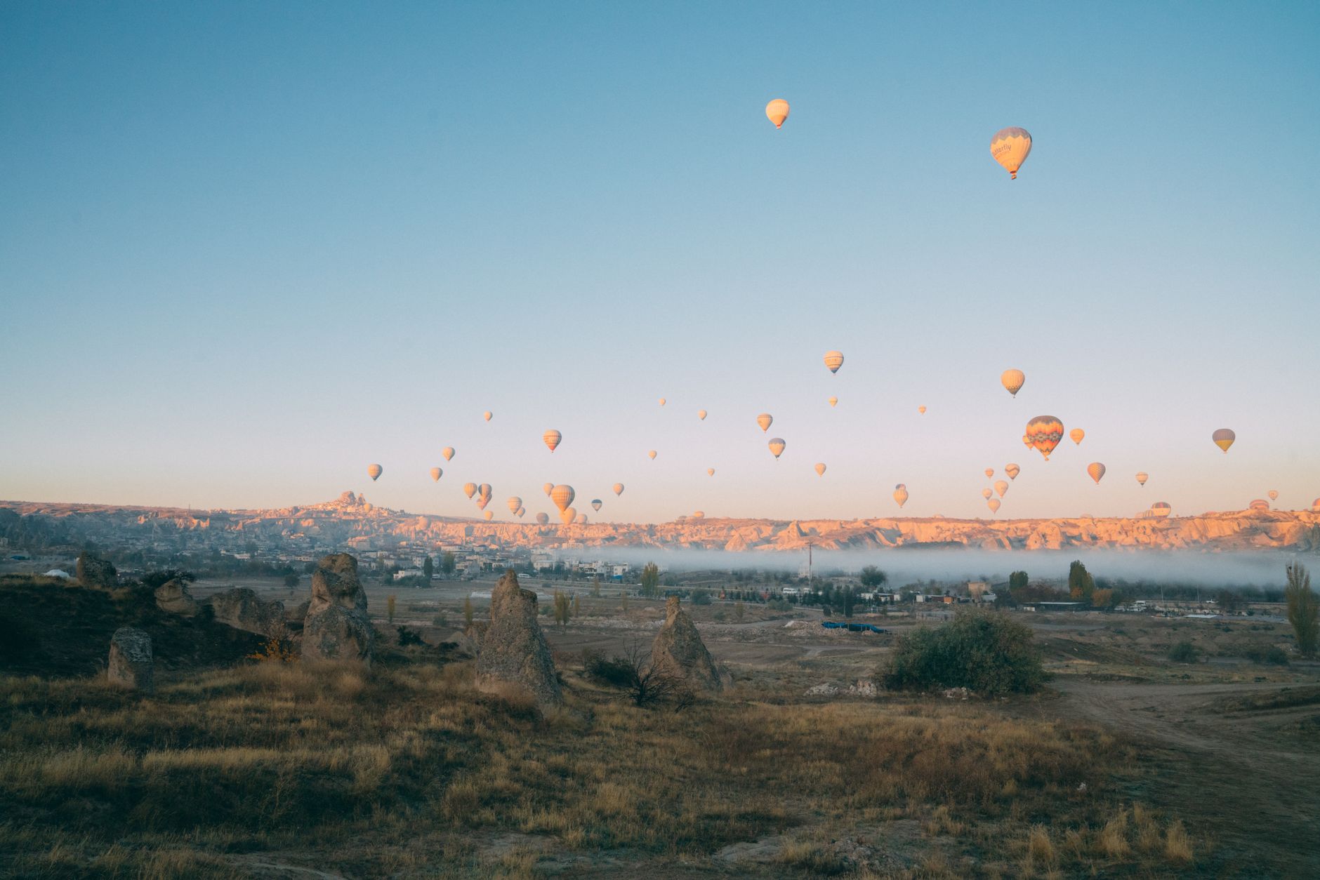 Gün doğumunda Kapadokya'nın pitoresk vadileri üzerinde süzülen rengârenk sıcak hava balonları.