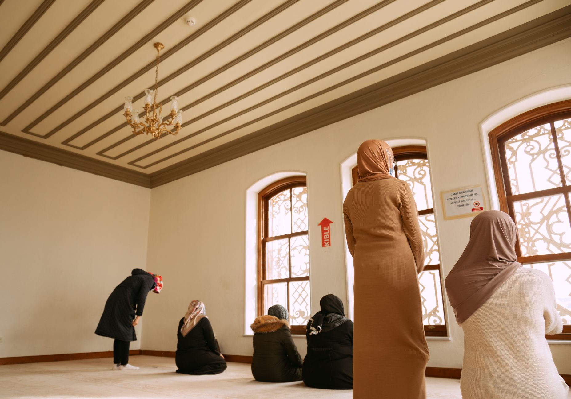 Women praying in a serene prayer room at Istanbul Airport.