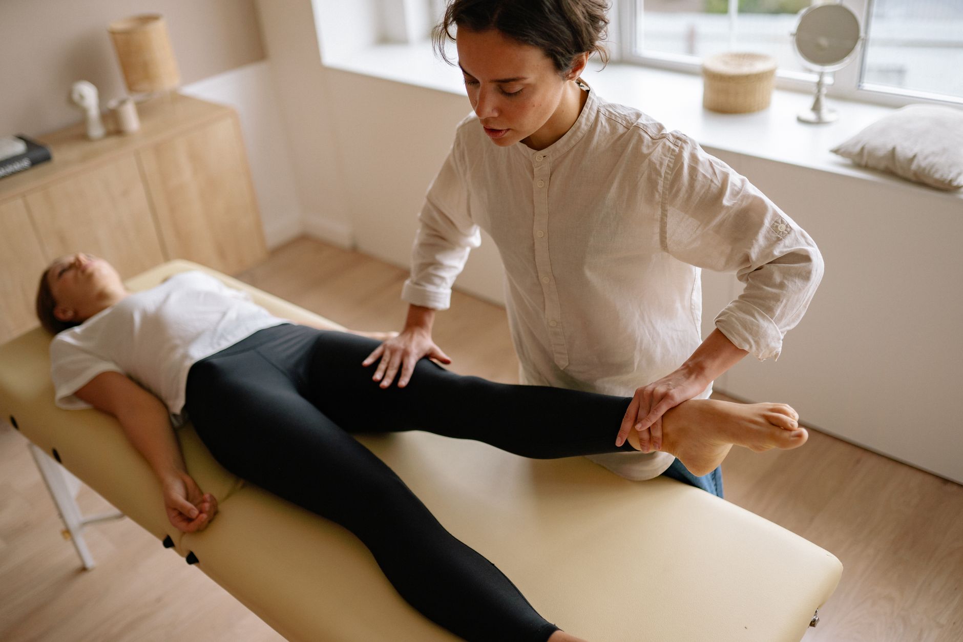 A therapist is guiding a patient through dexterity exercises in a bright therapy room.