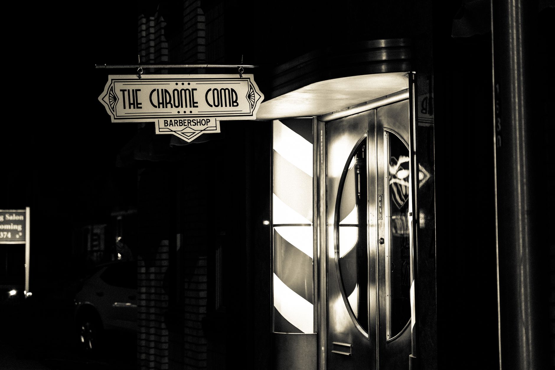 夜晚亮起的复古理发店招牌，写着The Chrome Comb。