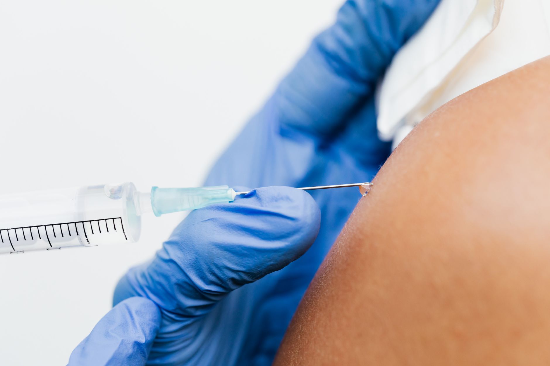 Close-up of a doctor giving a nerve block injection in a patient's shoulder.