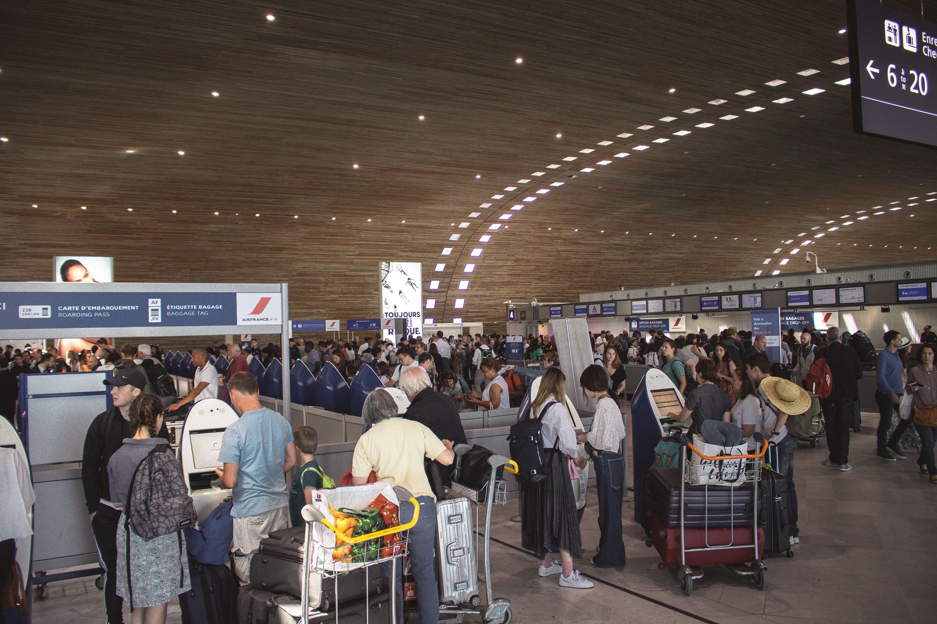 Passengers waiting in line at an airport check-in counter with baggage.