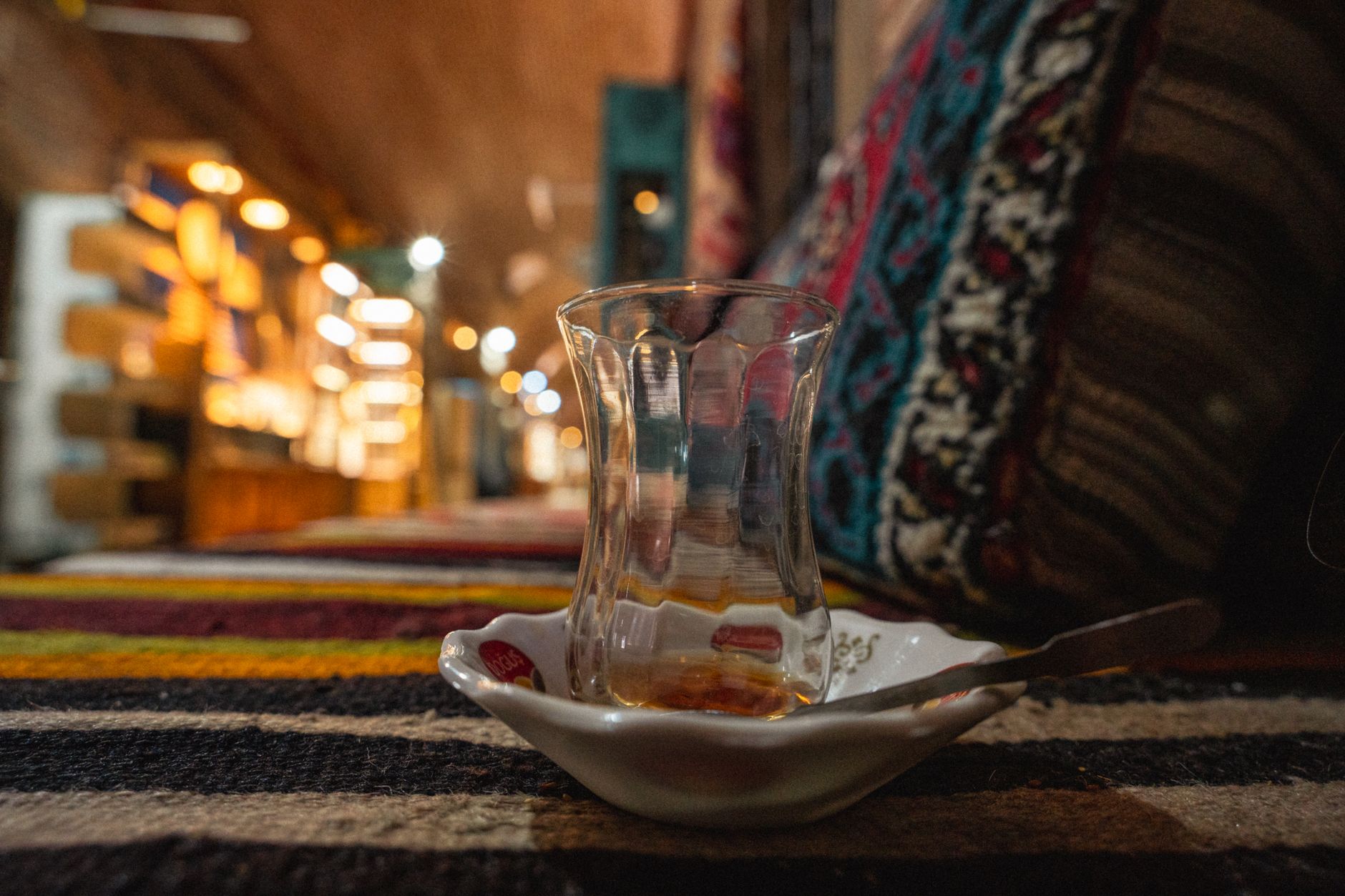 A glass of Turkish tea on a decorative saucer in a warm, inviting setting.