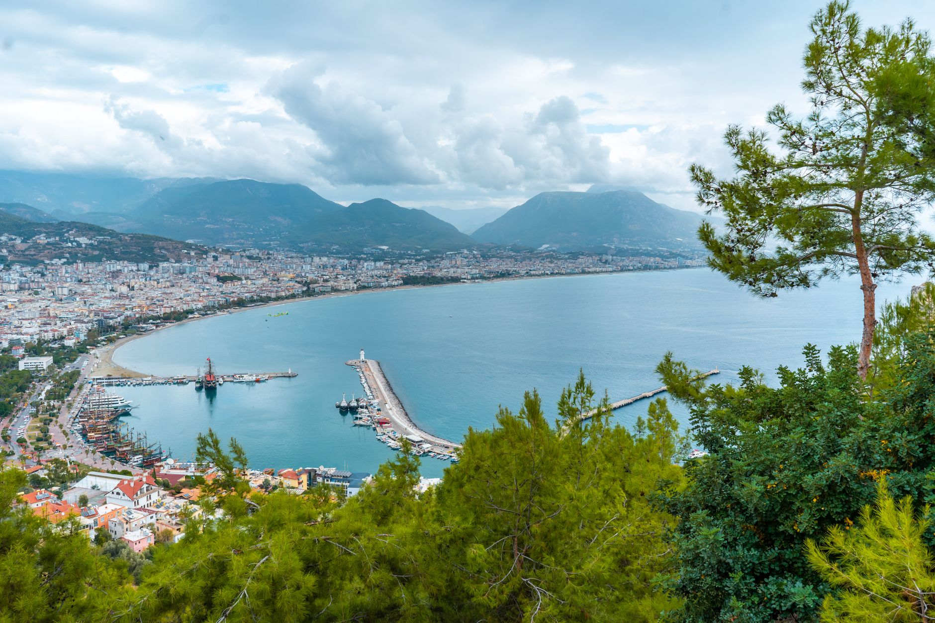 Panoramic view of Antalya coastline, featuring marina and mountains in the background.