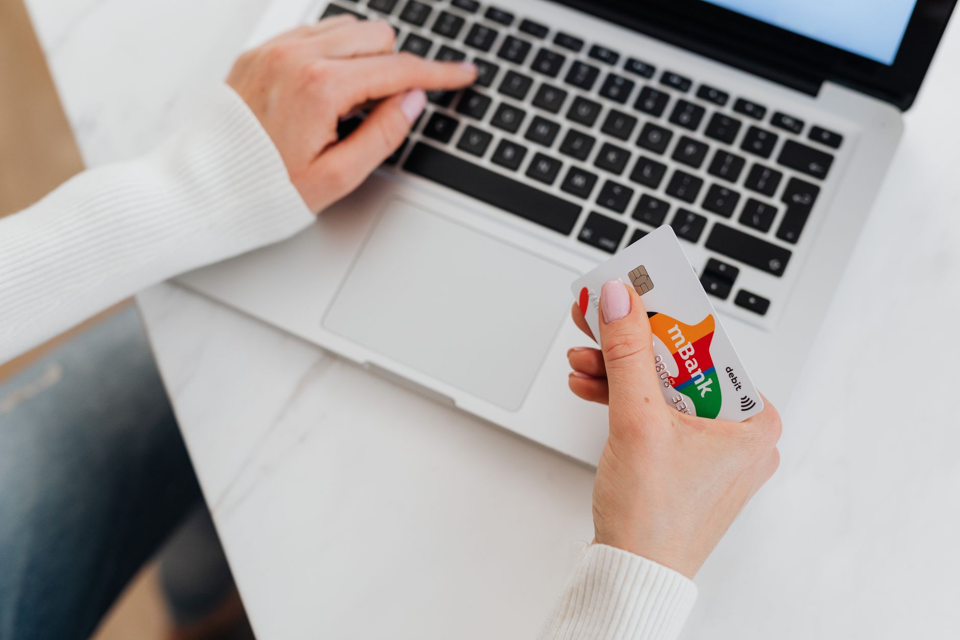 A person using a debit card to make a secure online payment on a laptop.