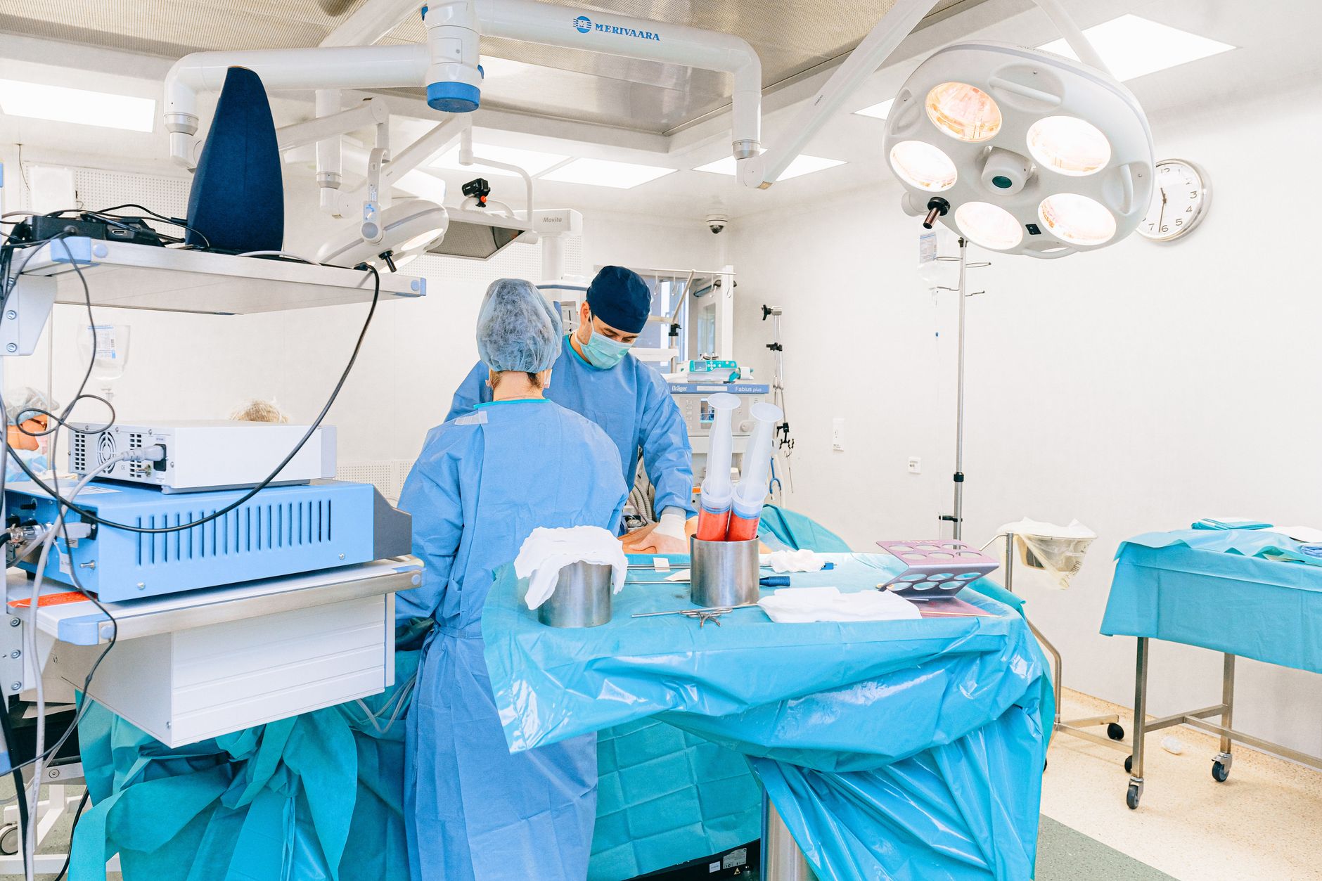 Surgeons in blue scrubs perform surgery in a sterile operating room.