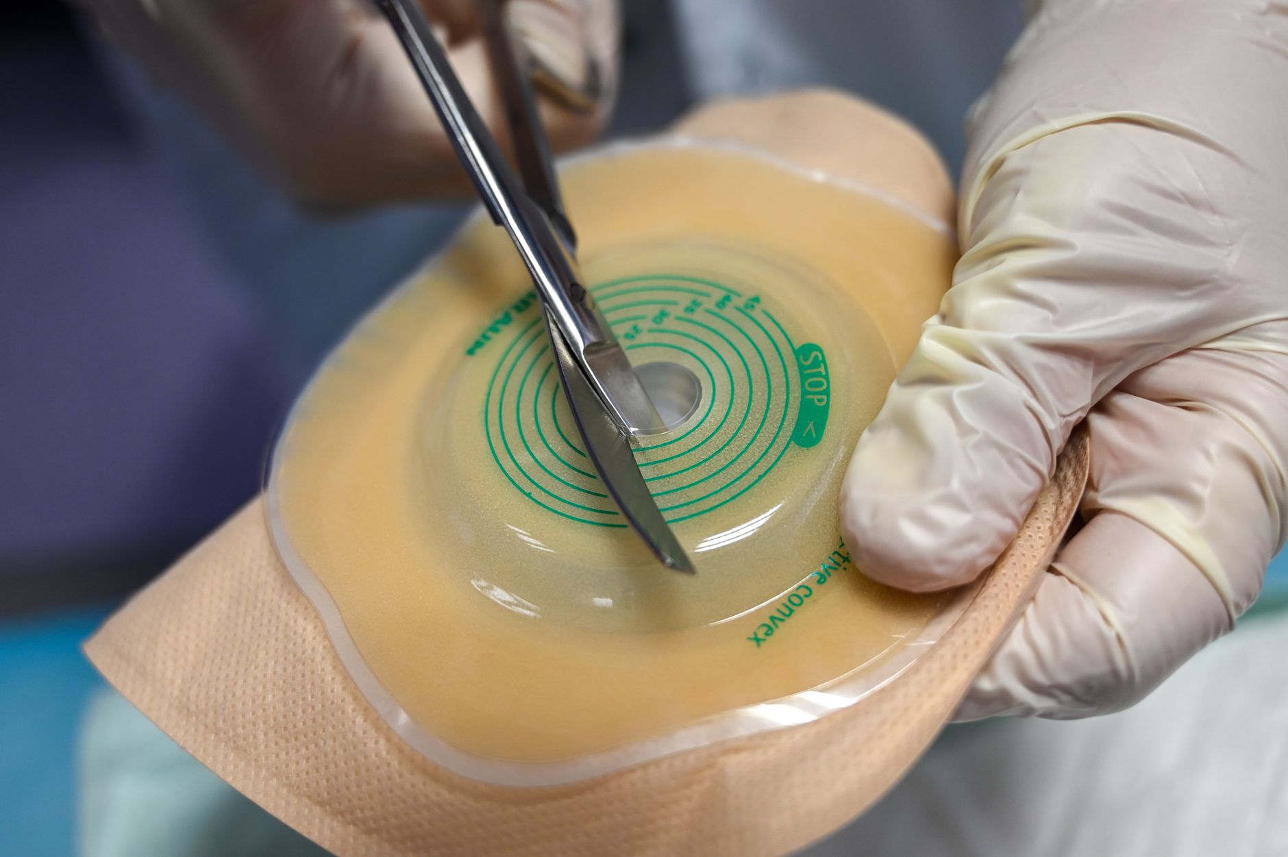 A medical professional cuts a device in a clinic, wearing gloves.