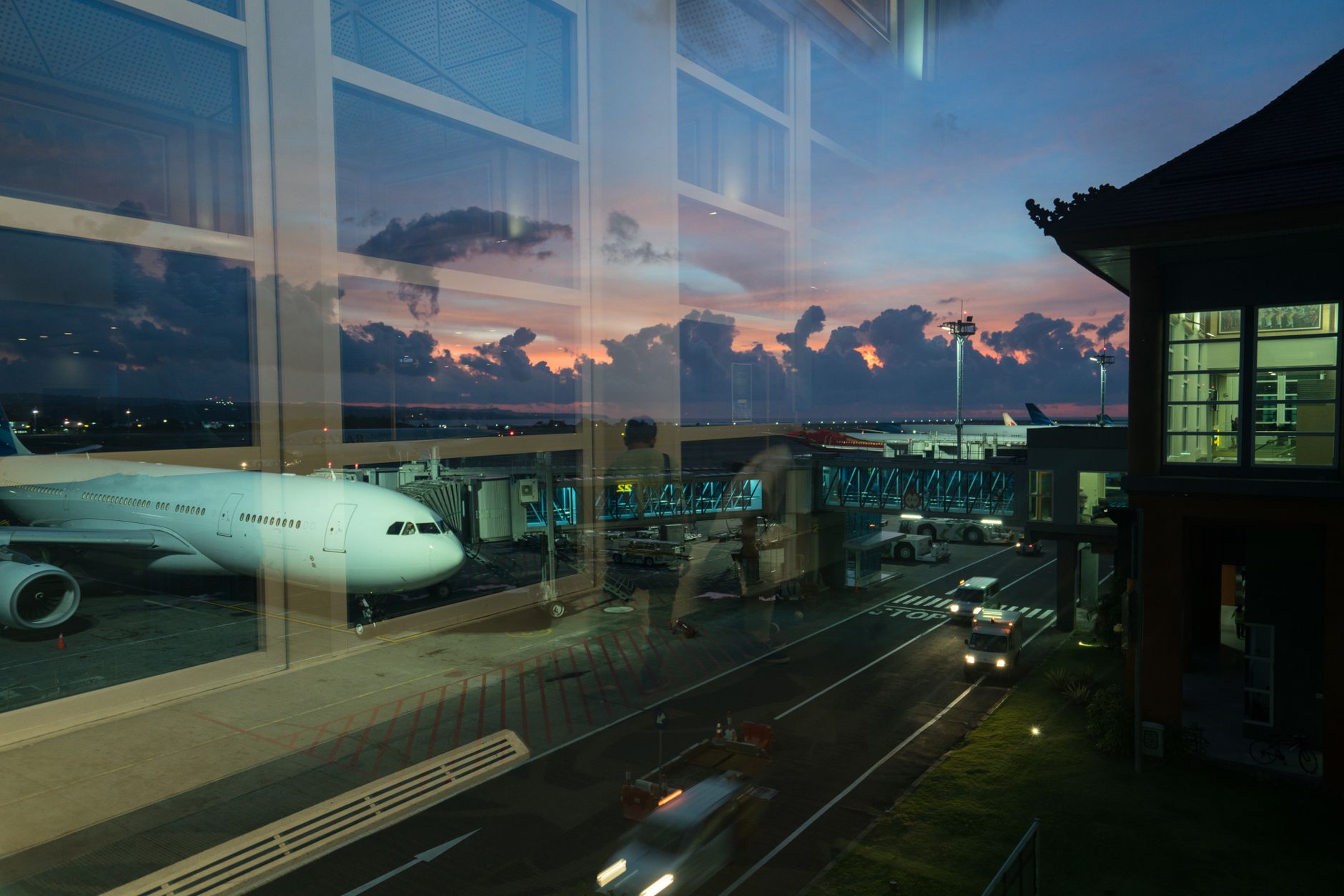 A serene airport scene at sunset, showcasing a waiting transfer car outside, ready for passengers.