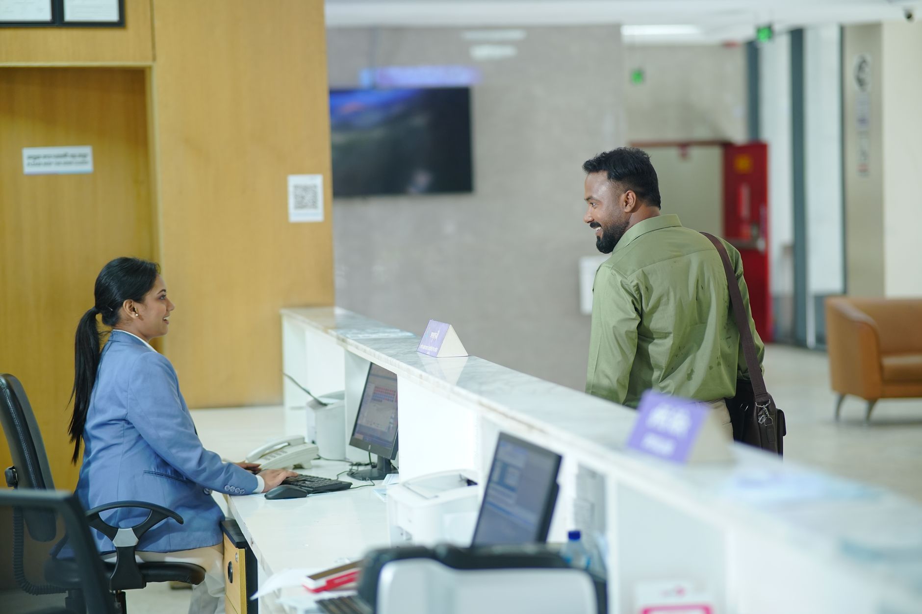 A receptionist smiling at a medical traveler at the reception desk.