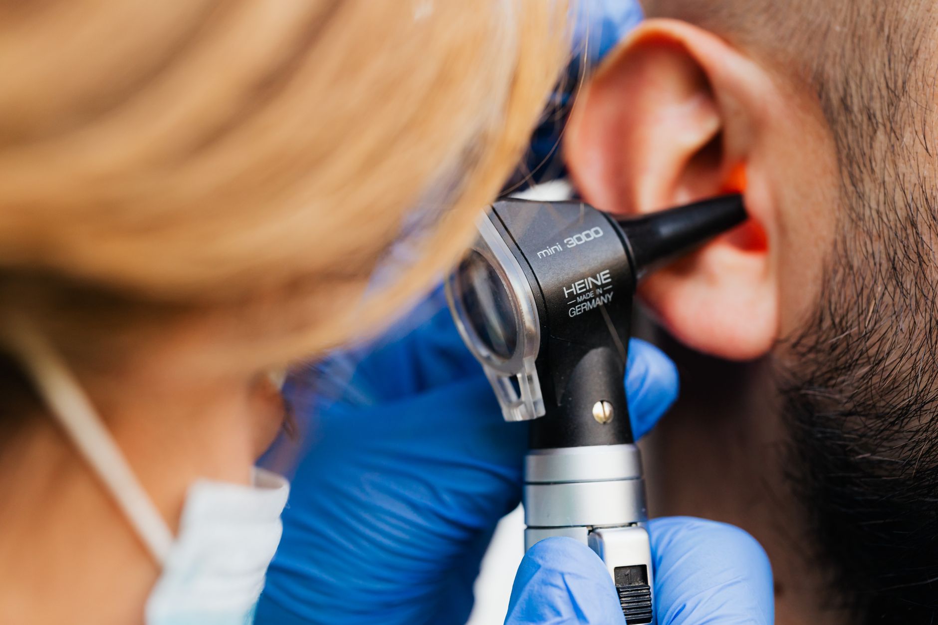 An ENT specialist using an otoscope on a patient's ear in a bright Turkish hospital.