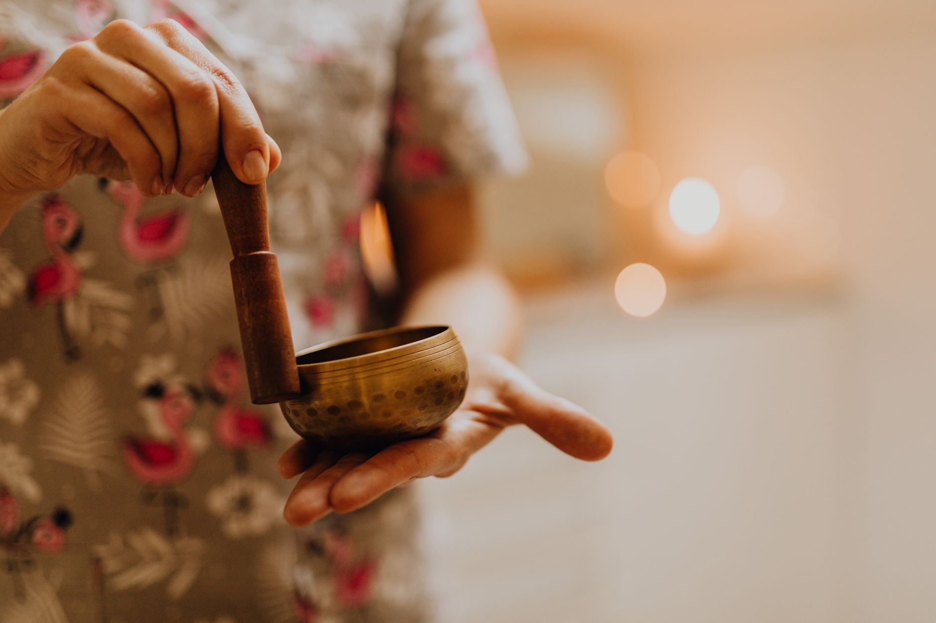 Close-up of a hand holding a singing bowl and mallet in a tranquil consultation room.