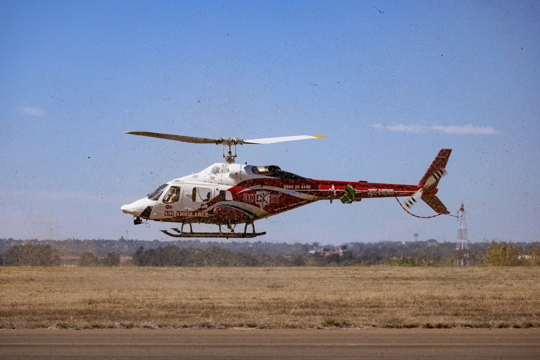 A red and white air ambulance helicopter takes off, showcasing emergency medical services for patient transport.