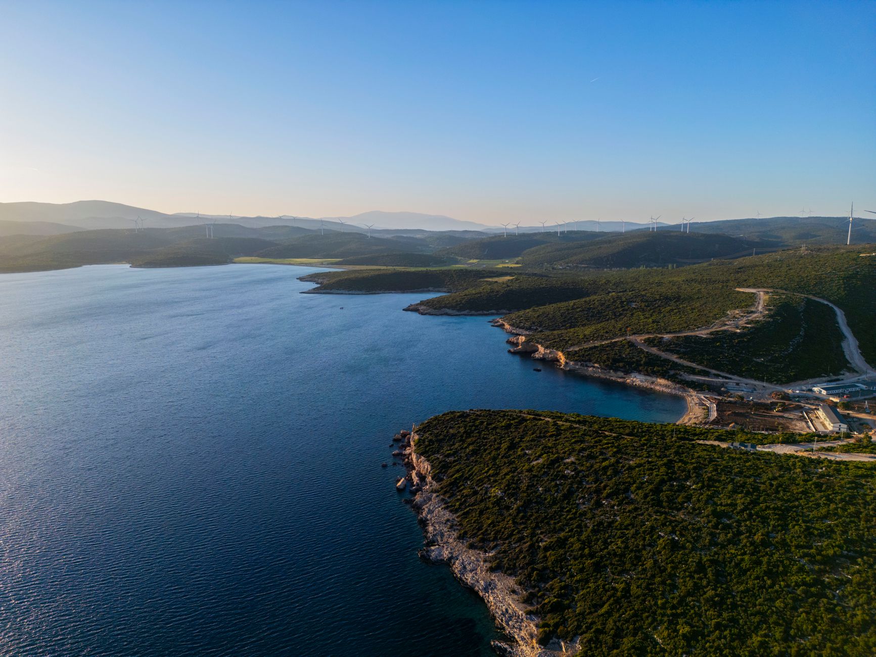 Aerial view of the İzmir Aegean coastline, showcasing green hills and blue waters.