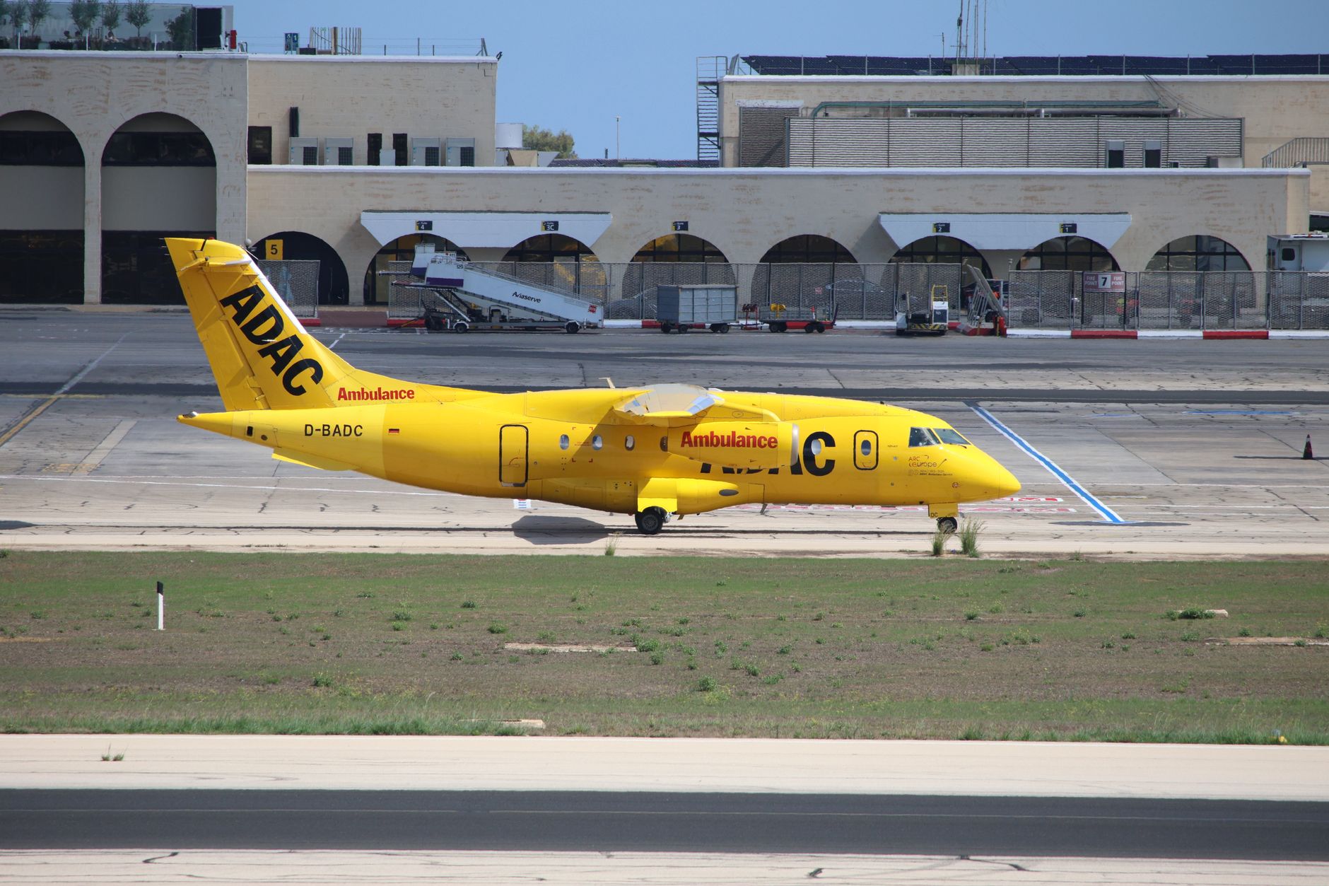 Yellow ADAC ambulance aircraft D-BADC parked on airport tarmac, ready for medical transfer.
