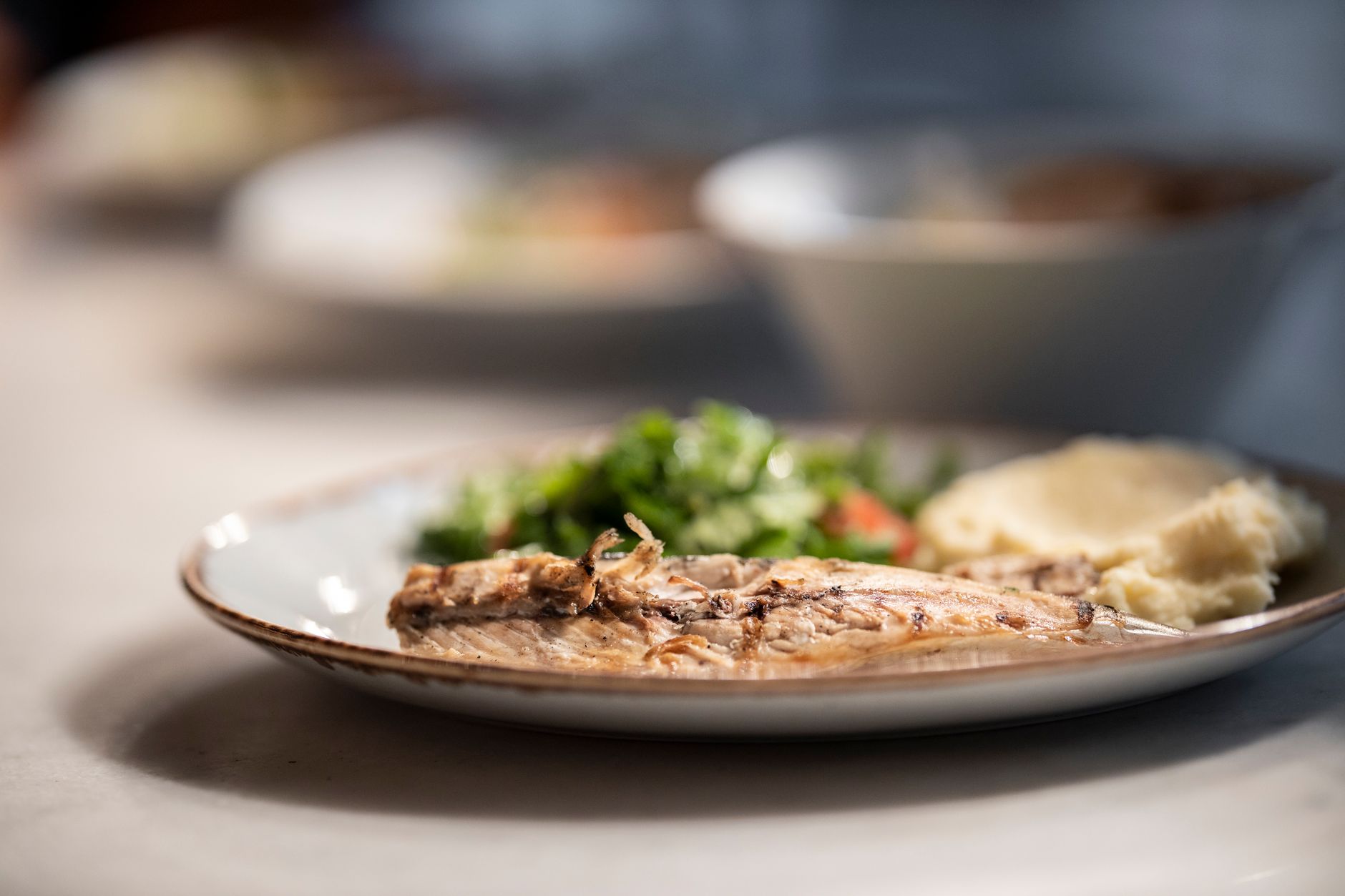 Plate of grilled fish served with fresh salad and mashed potatoes, showcasing Mediterranean diet.