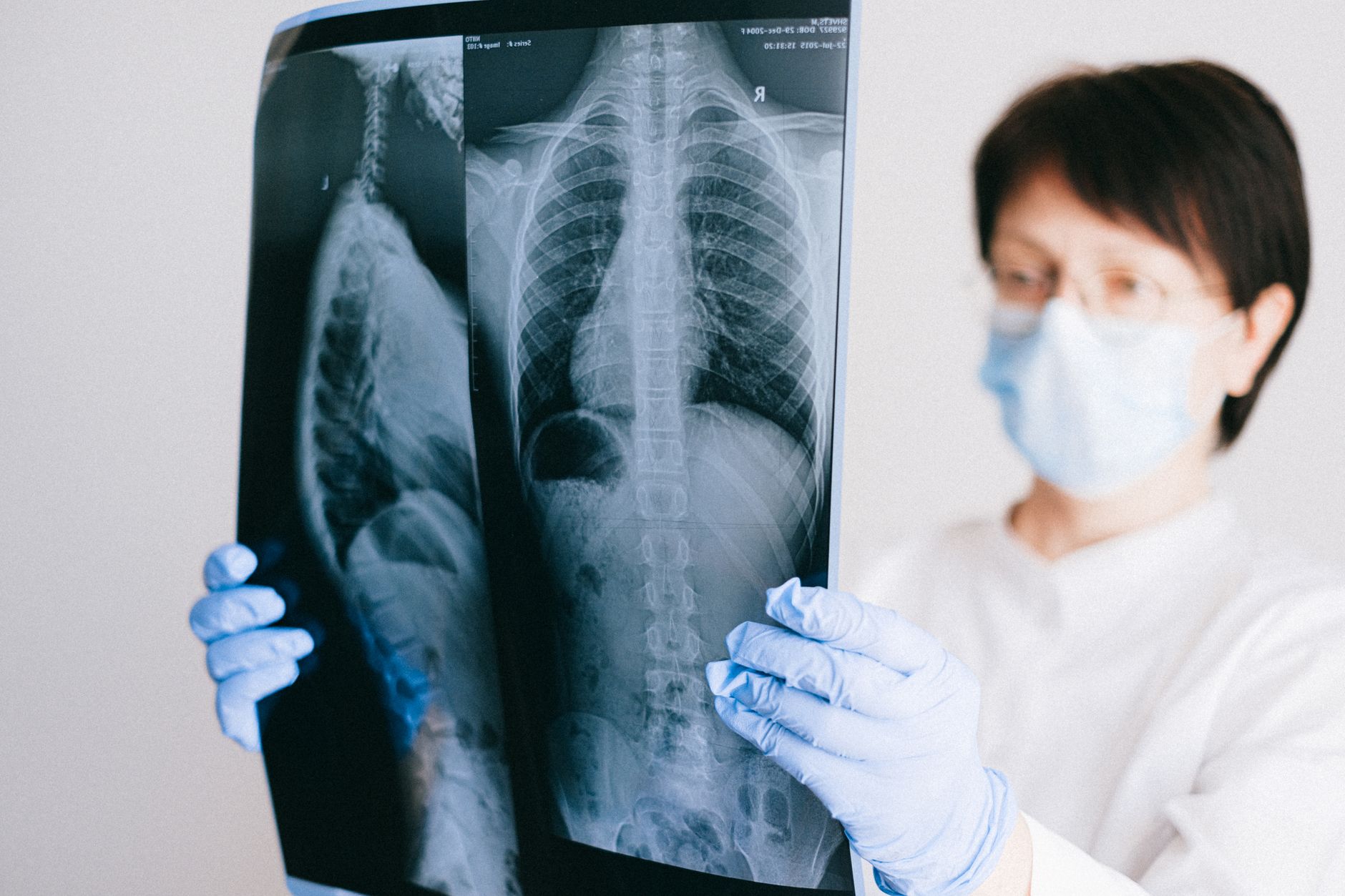 A radiologist in a mask examines lung CT images for analysis.