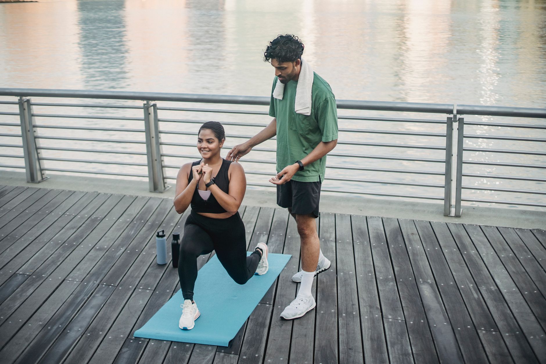 A lifestyle coach assists a woman with lunges at a park by the water in Istanbul.