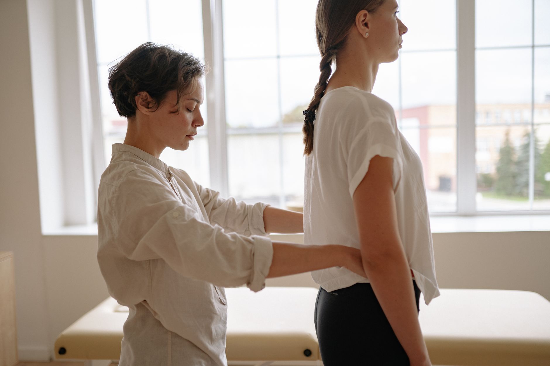 A therapist guides a patient through balance exercises in a rehabilitation gym, focusing on posture and alignment.