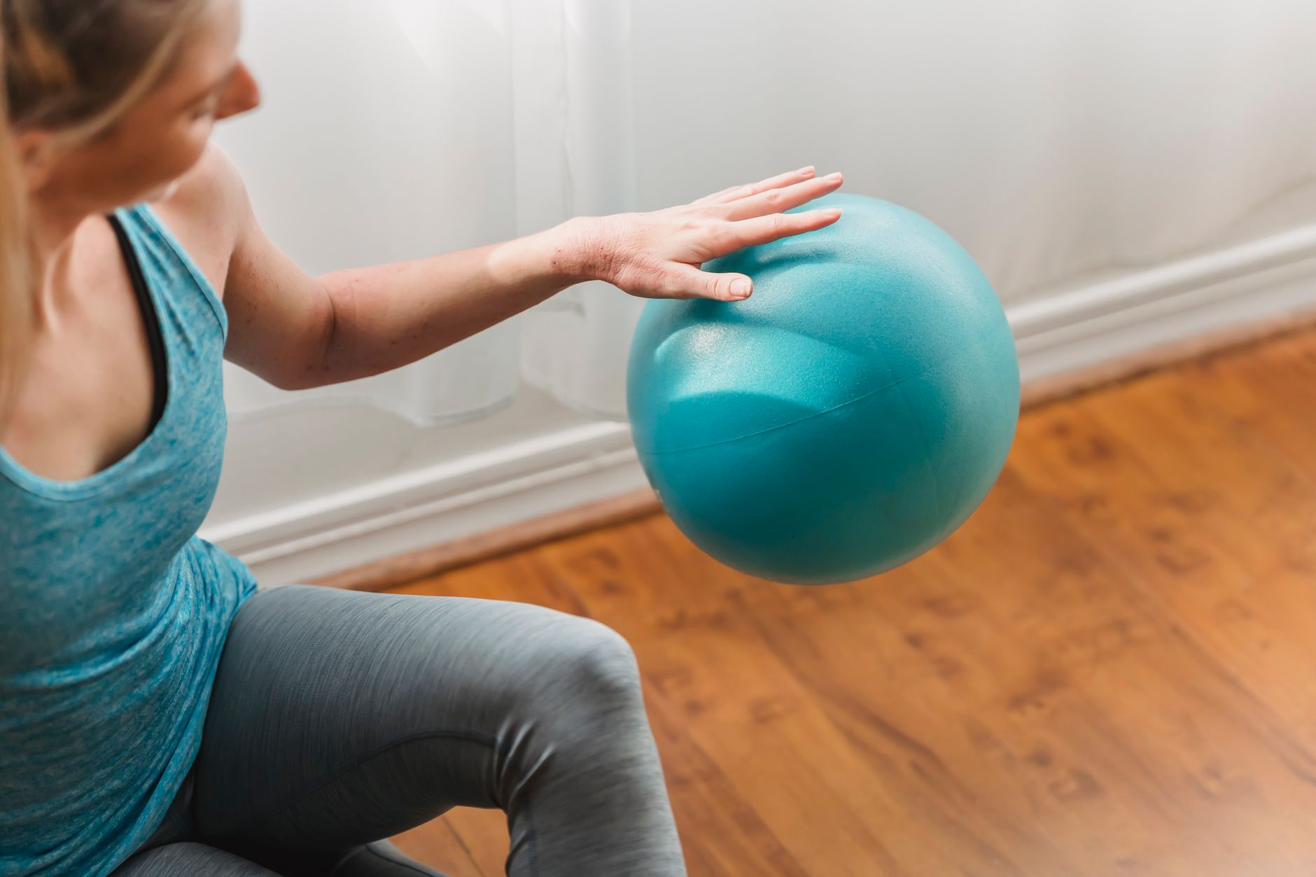 A patient performs balance exercises at home using a stability ball.