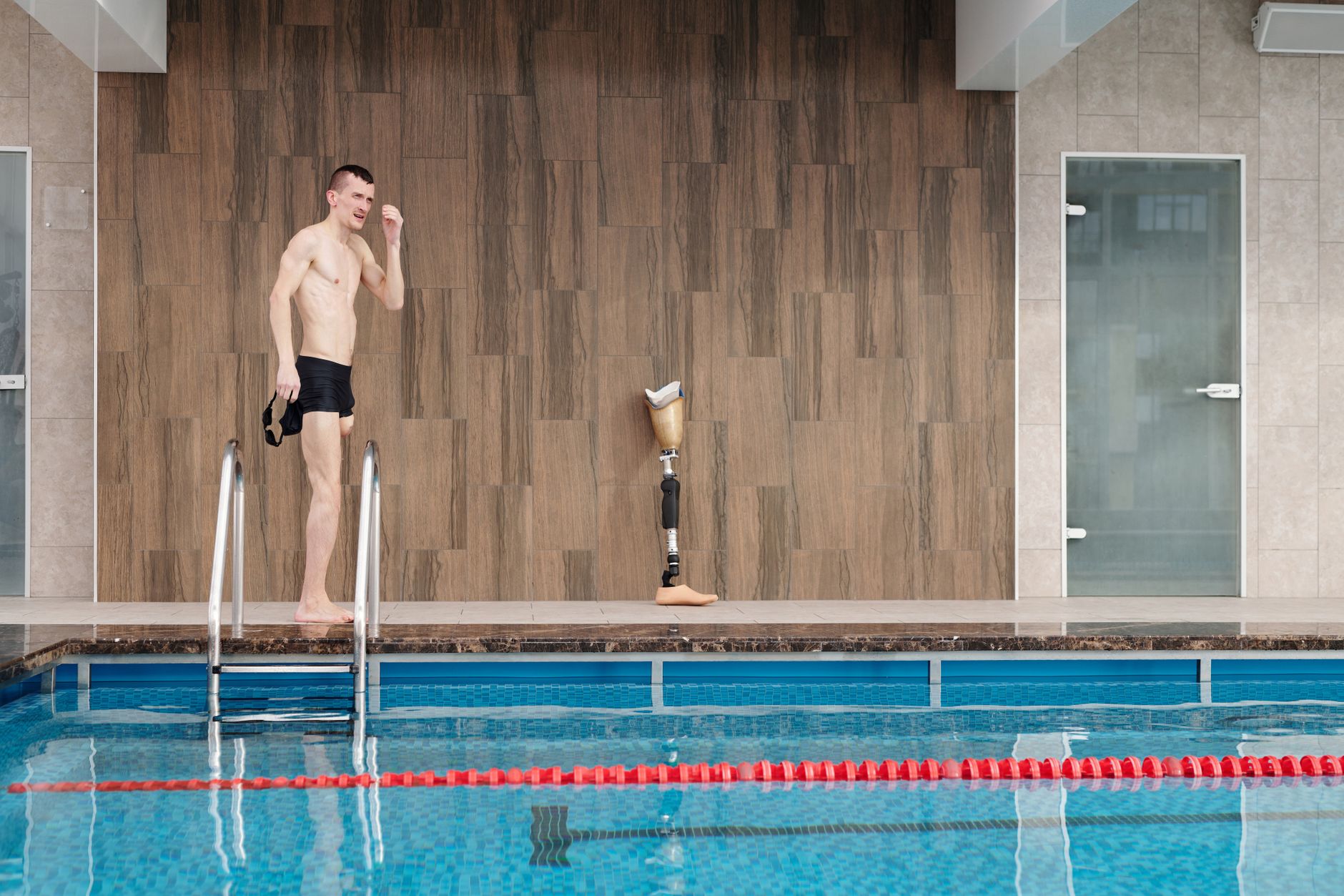A man stands at the edge of a warm water therapy pool, preparing to exercise.
