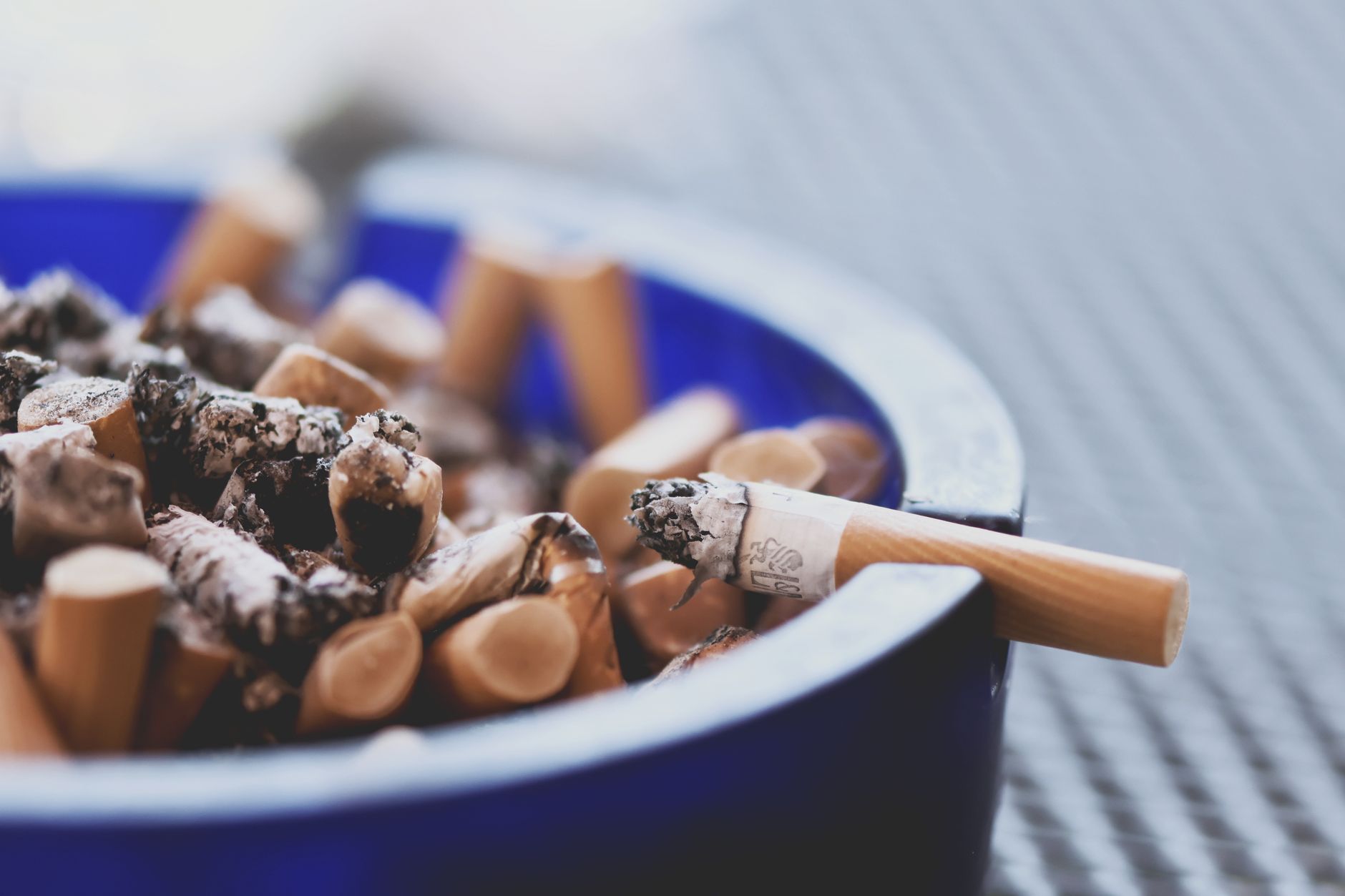 Close-up of an ashtray filled with cigarette butts, symbolizing smoking cessation efforts.