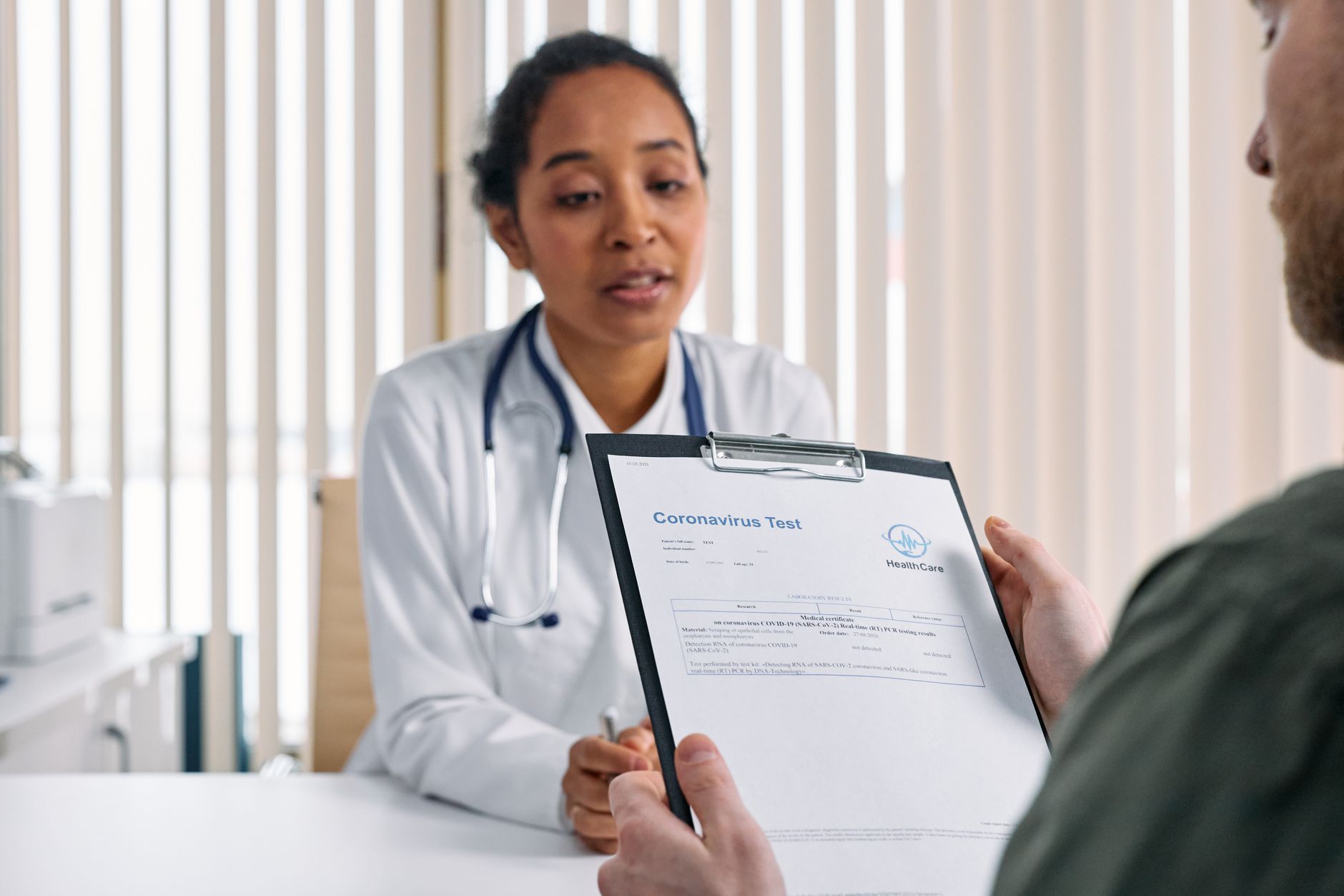 A doctor reviews a coronavirus test result with a patient in a clinic.