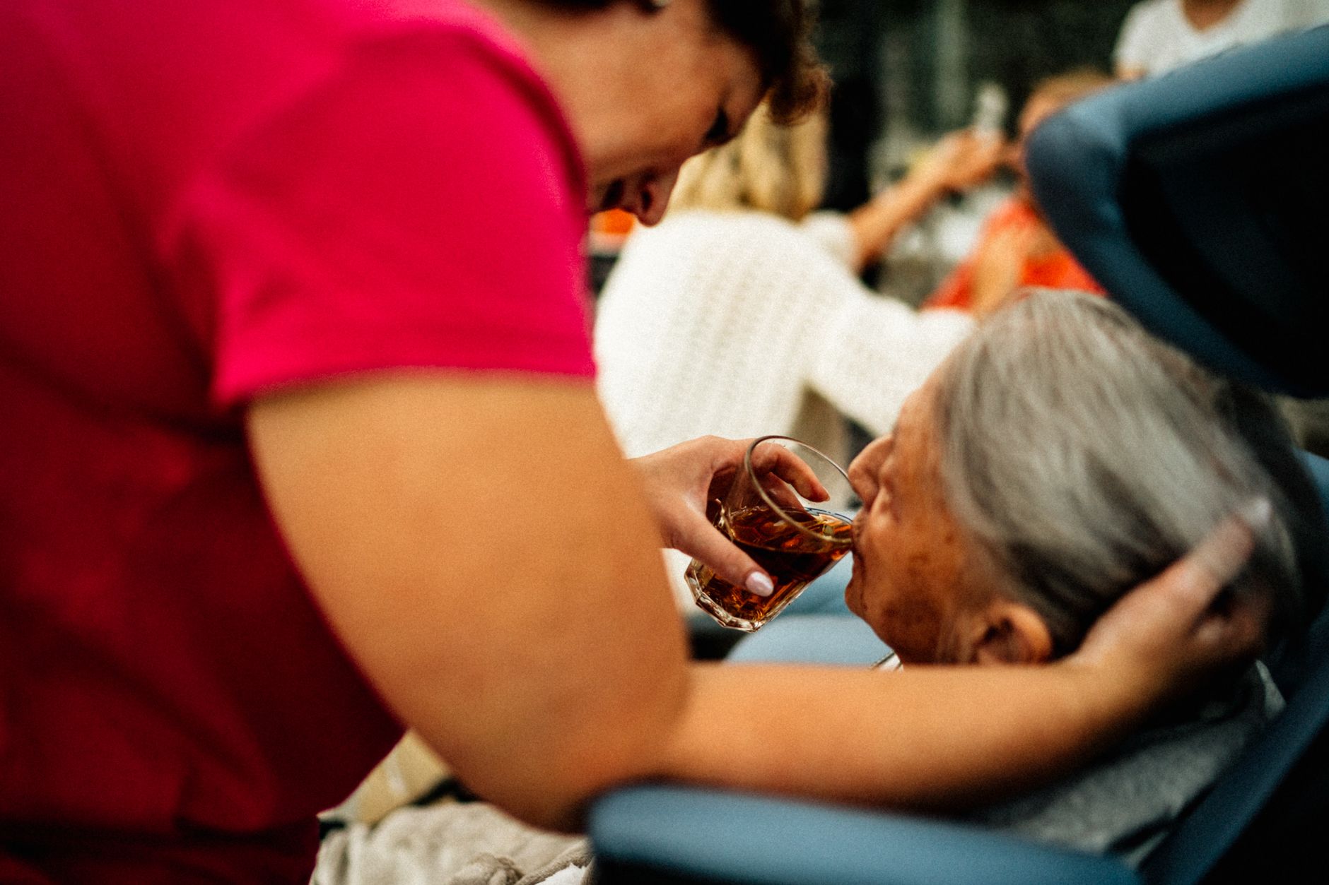 A nurse assists an elderly patient with a drink, showcasing gentle care.