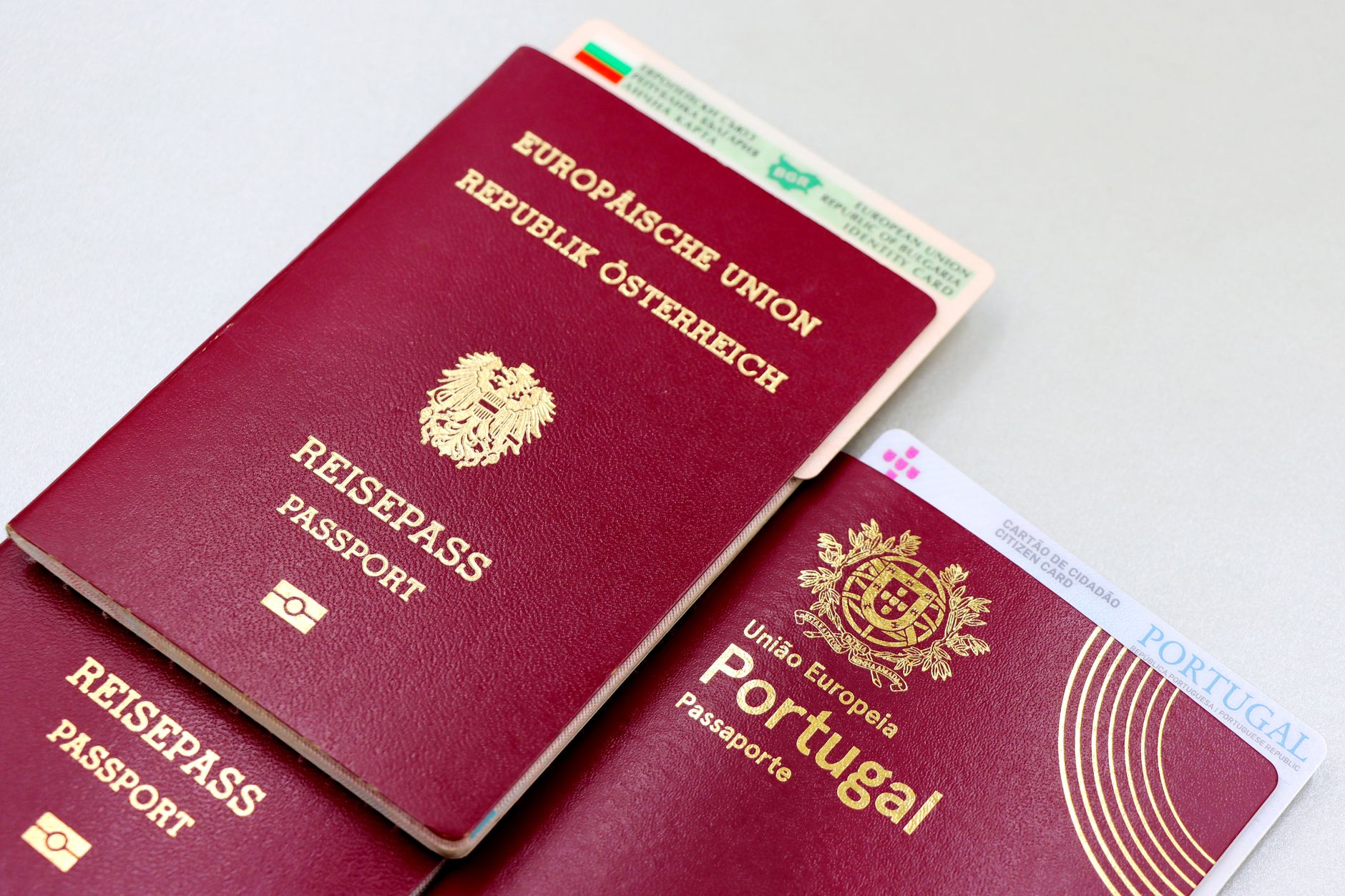 A close-up of Austrian and Portuguese passports with a citizen card on a table.