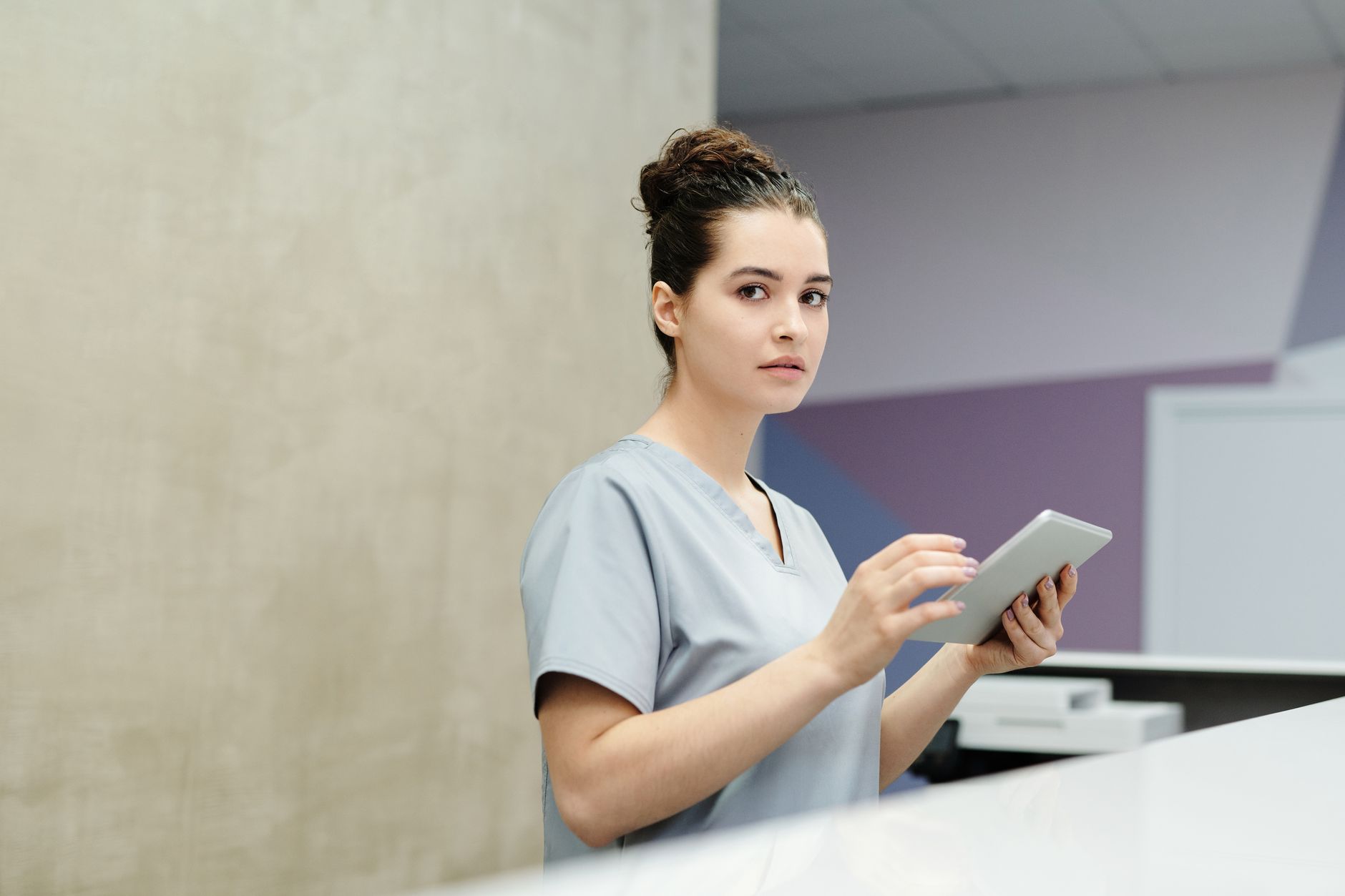 Multilingual staff member at an international patient department desk, holding a tablet.