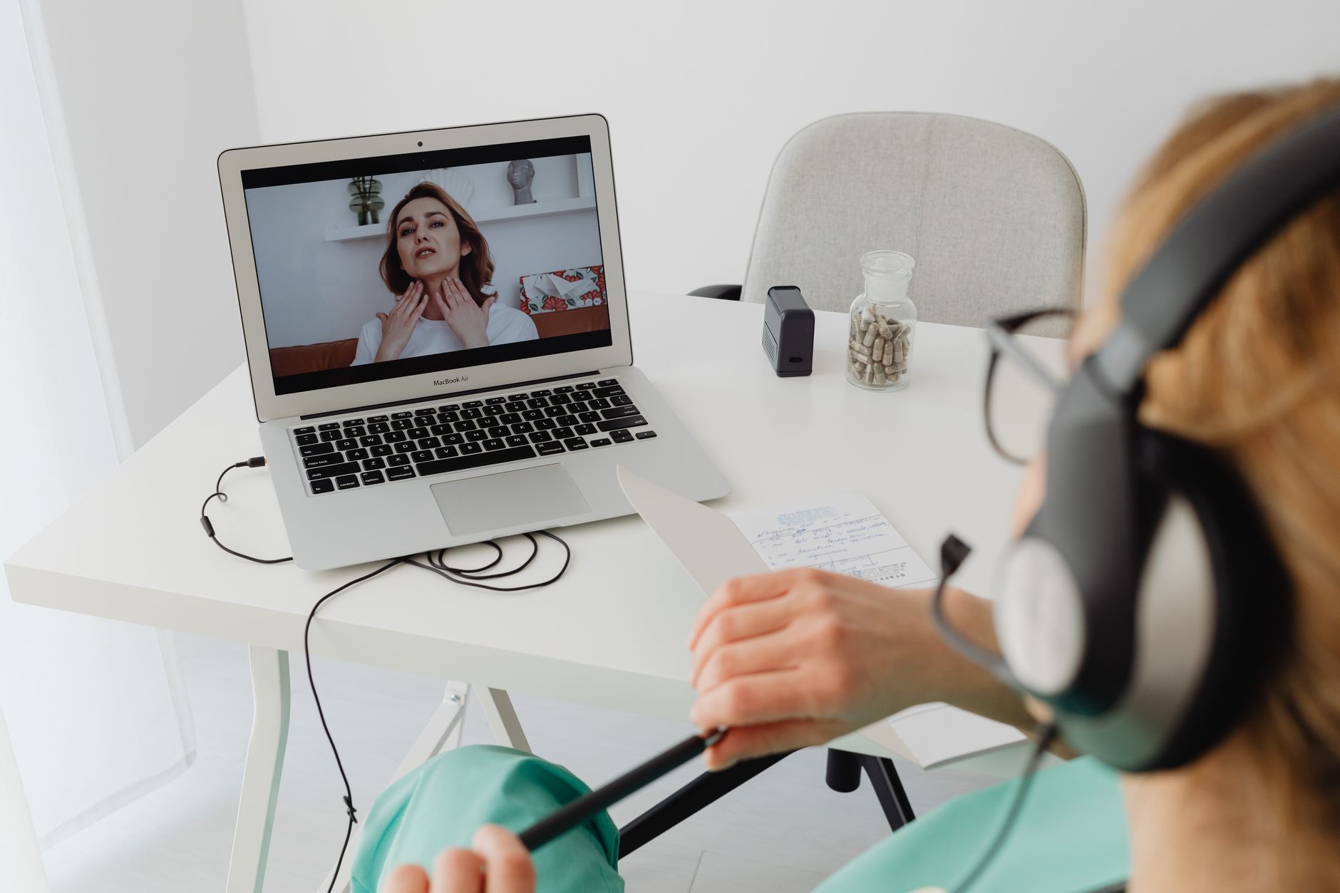 A patient in a teal outfit on a video call with a doctor, discussing health matters.