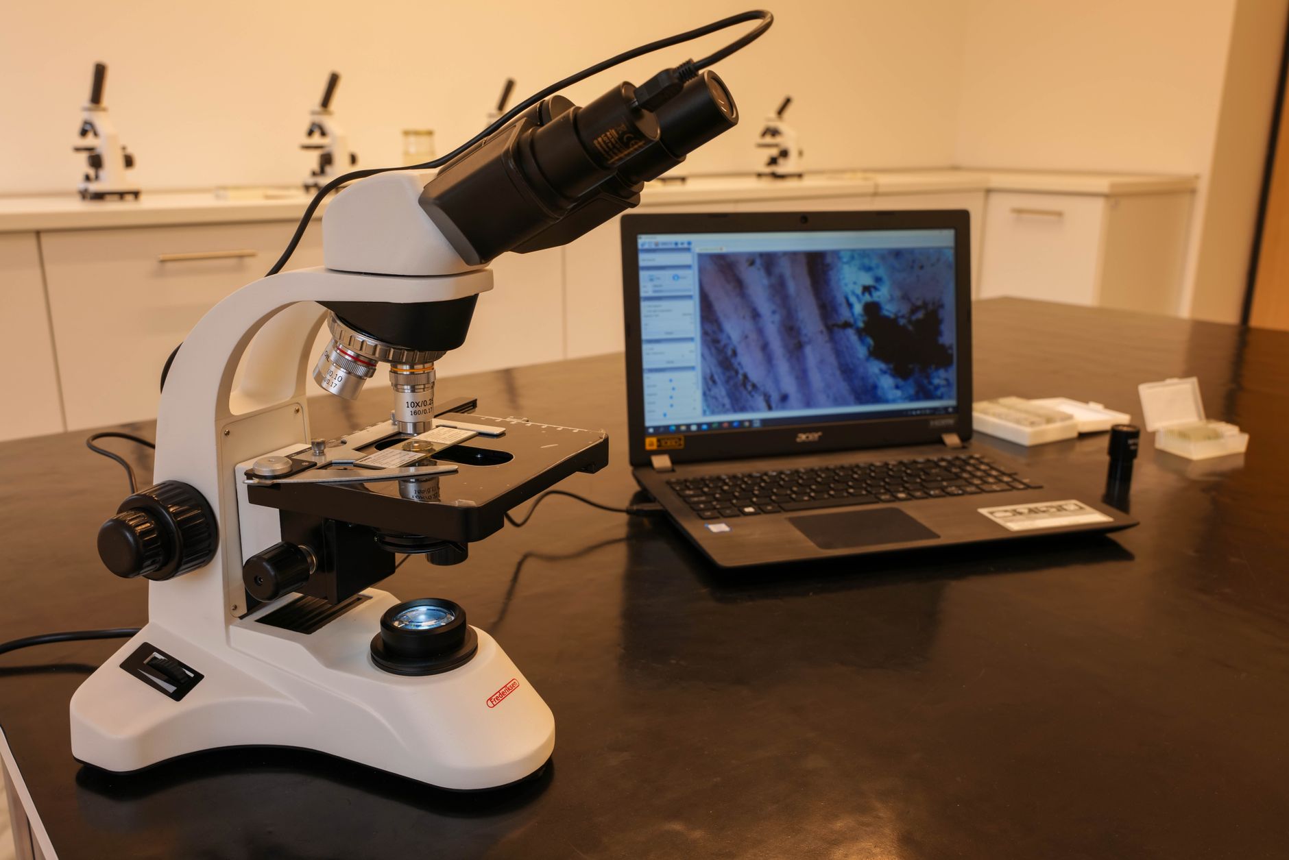 Microscope and laptop displaying imagery in a fertility lab for embryo screening.