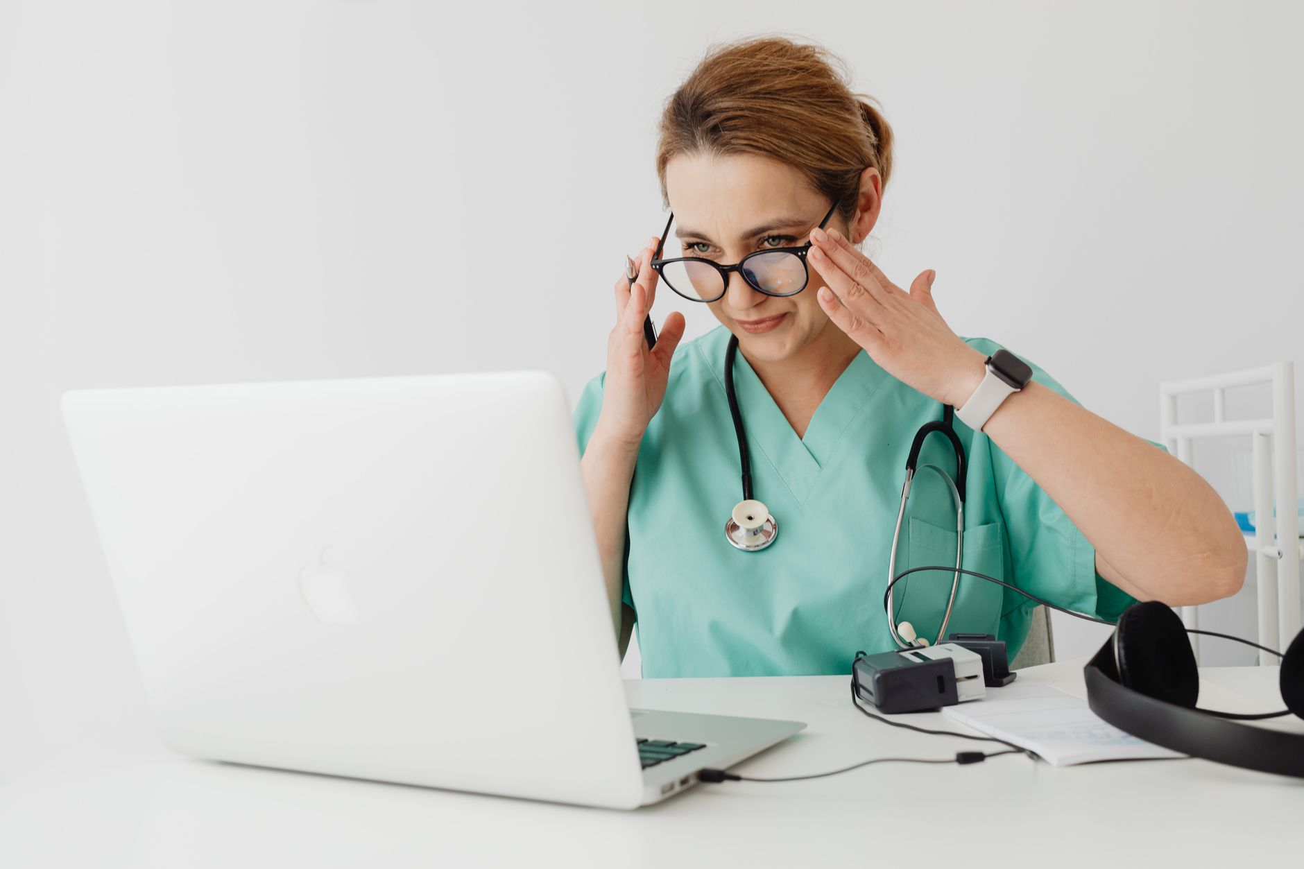 A healthcare professional in scrubs accessing a health tourism portal on a laptop.