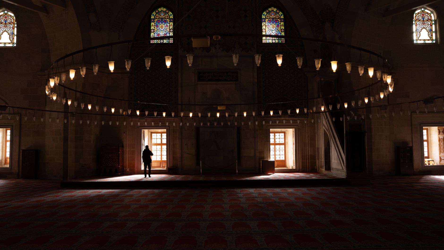 A tranquil mosque interior featuring stained glass windows and soft lighting.