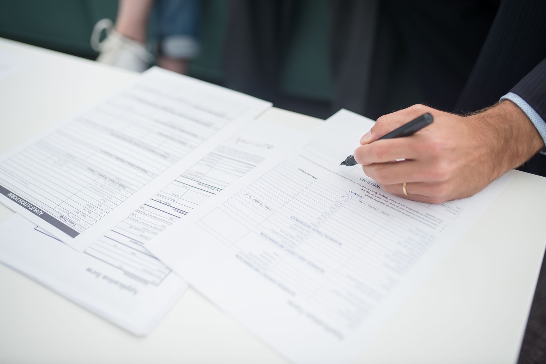A person filling out forms for a complication insurance policy on a desk.