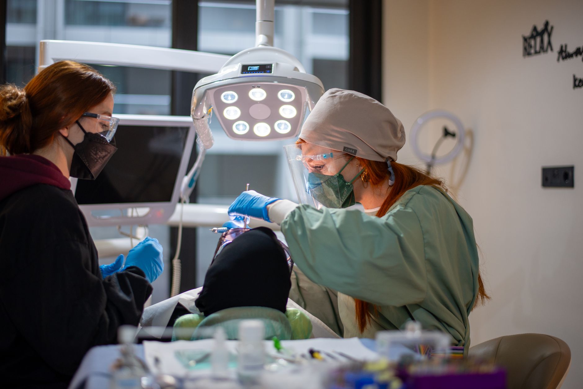 یک متخصص دندان‌پزشکی در کلینیکی مدرن در ازمیر بیمار را درمان می‌کند و نشان‌دهنده مراقبت است.