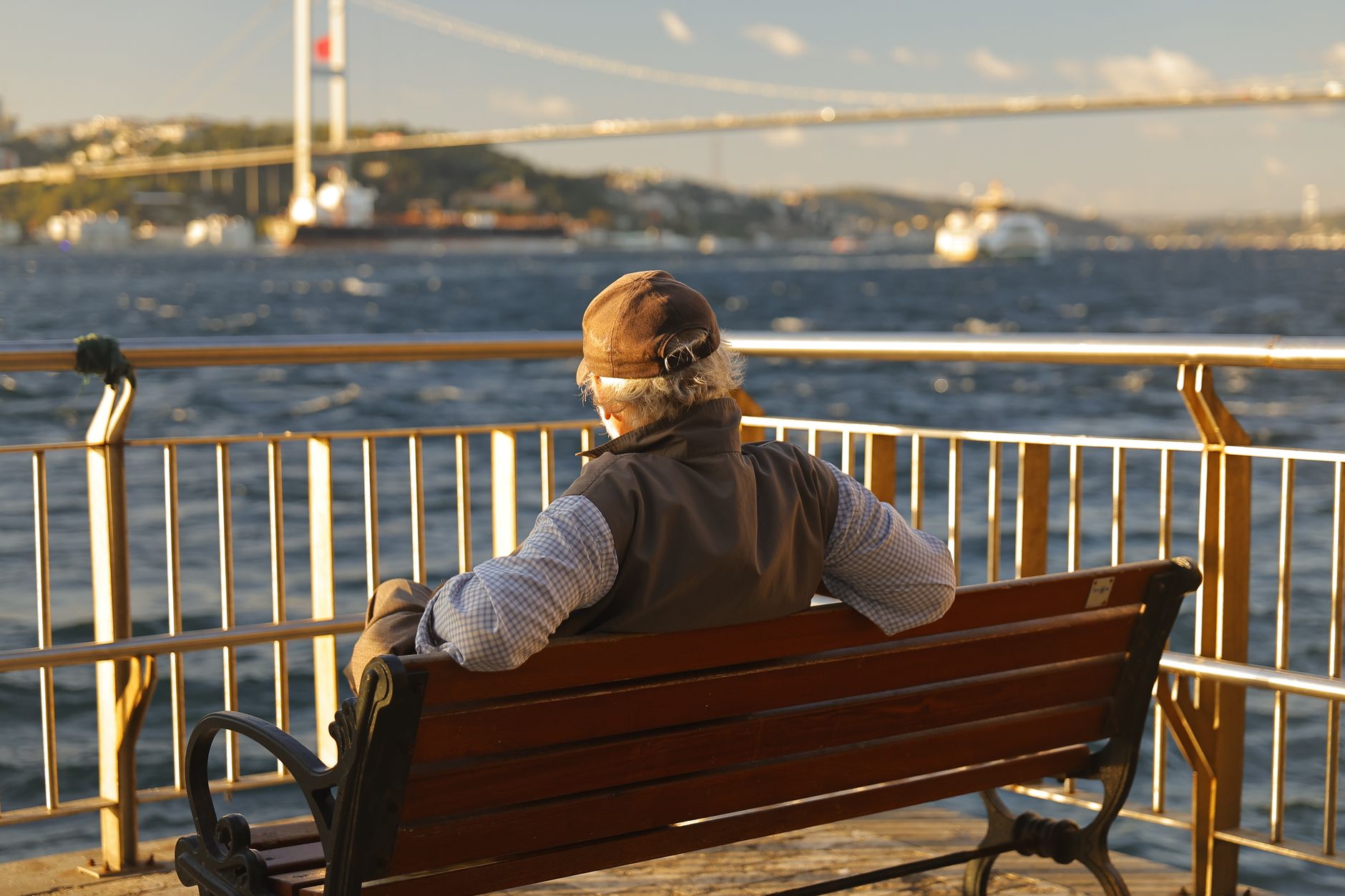 Older man sitting on a bench, gazing at the Bosphorus in Istanbul.