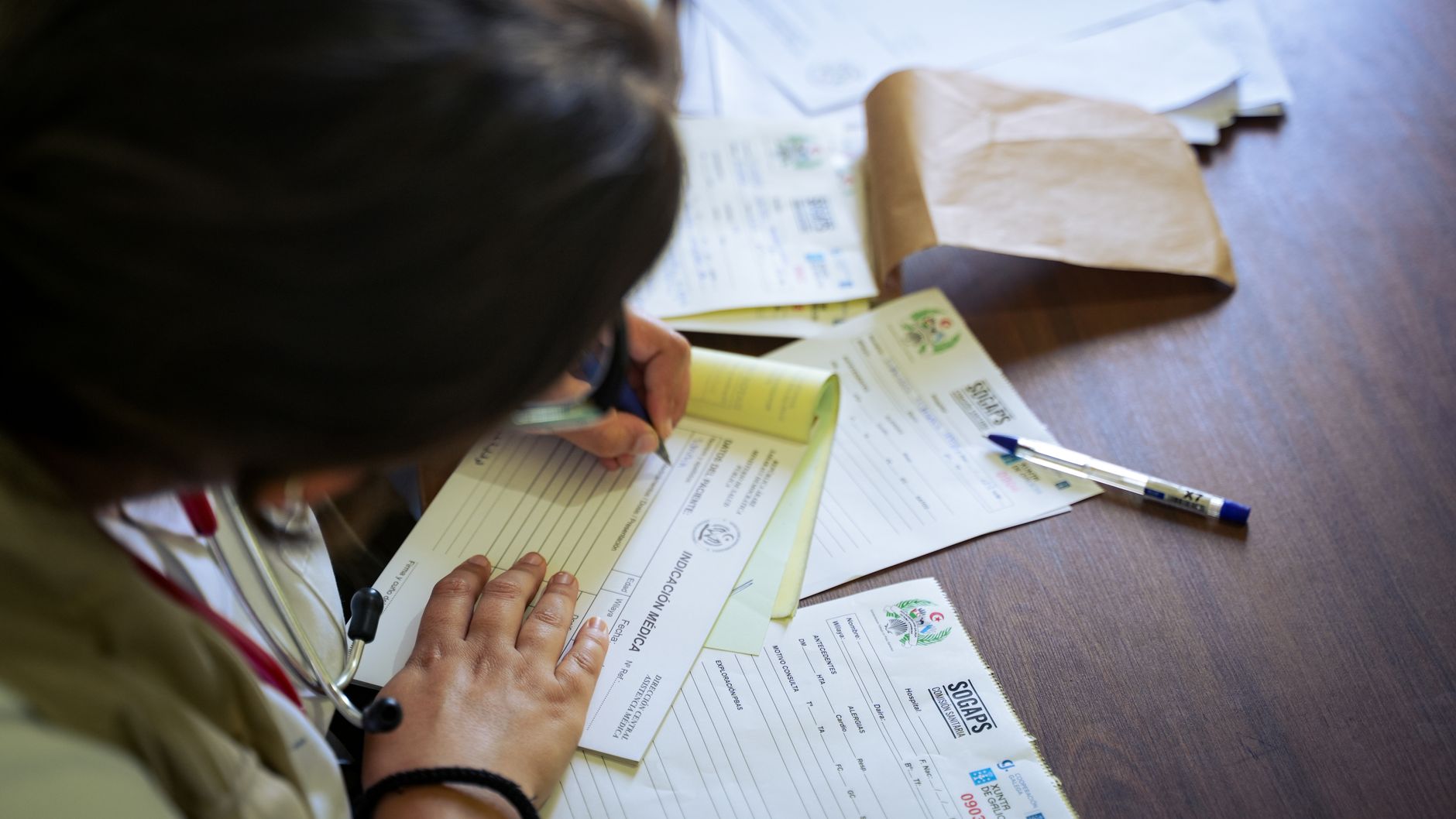A person filling out NHS-style medical forms at a desk, emphasizing health documentation.