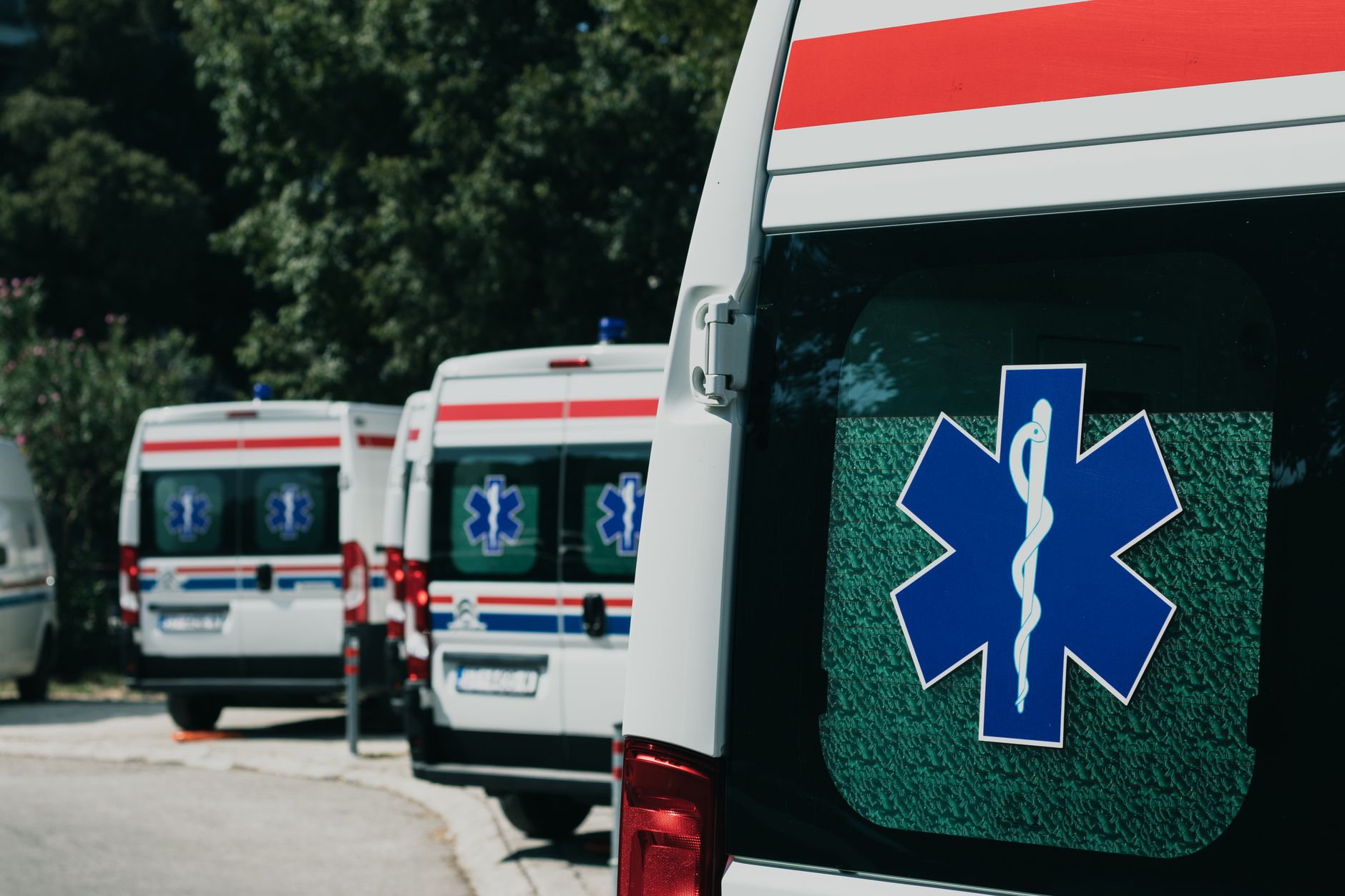 Line of private medical transfer vehicles with medical symbols parked outside an airport in Istanbul.