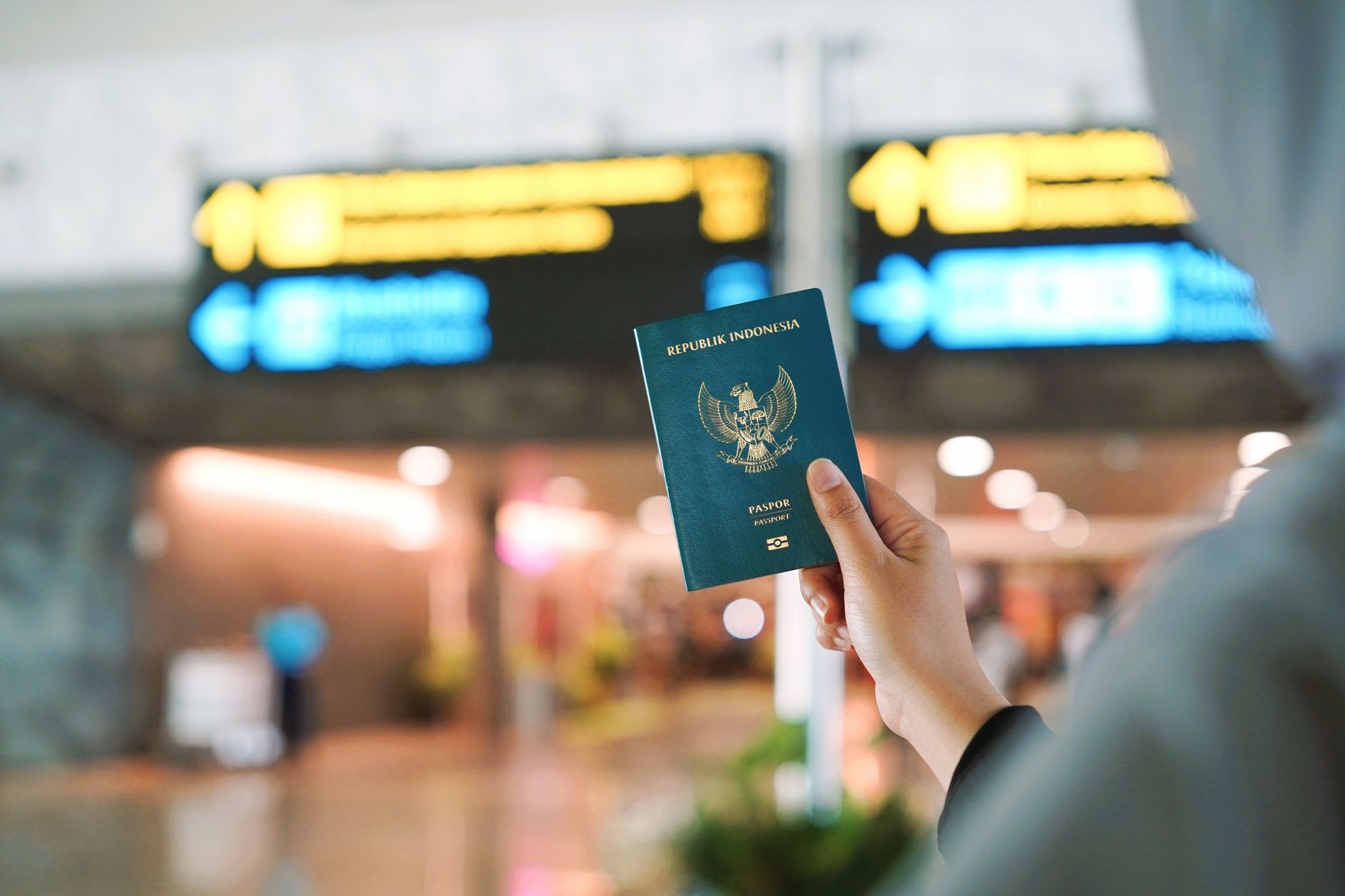 An Indonesian passport held at a Turkish airport's fast-track lane signage.