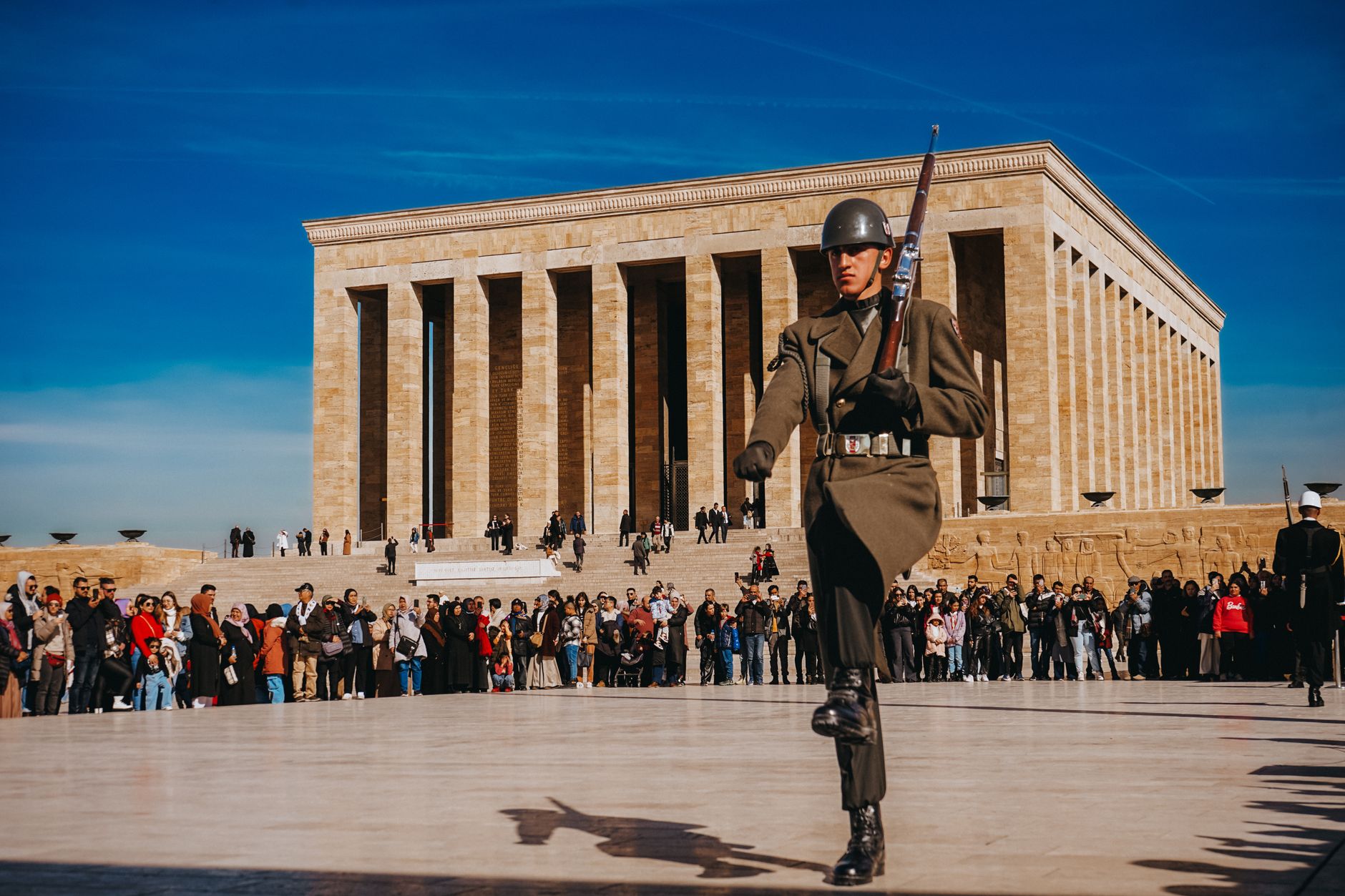Anıtkabir'de üniformalı bir asker, kalabalık seyirciler arasında yürüyor.