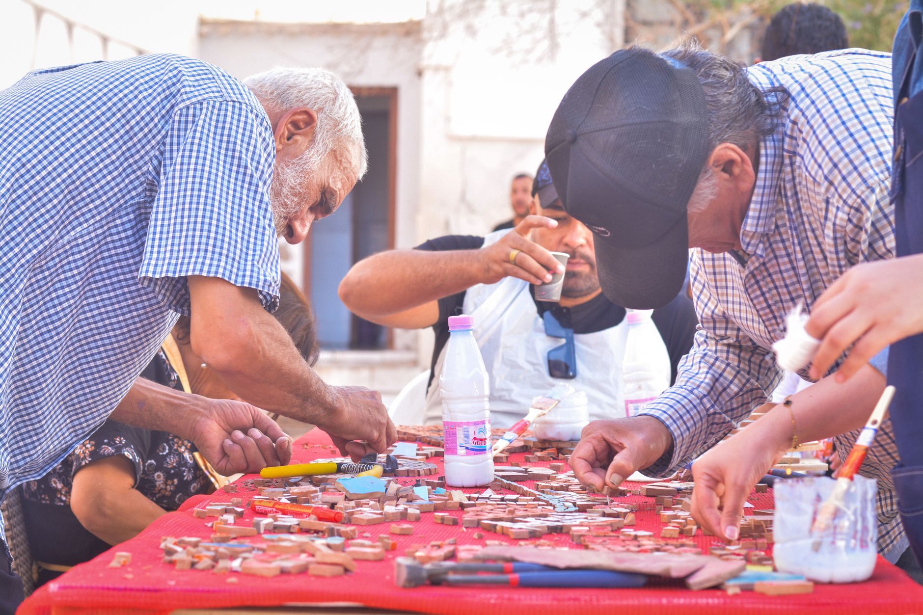 مسافرون يصنعون فسيفساء ملونة في ورشة بعنتاب، مع التركيز على القطع المعقدة.