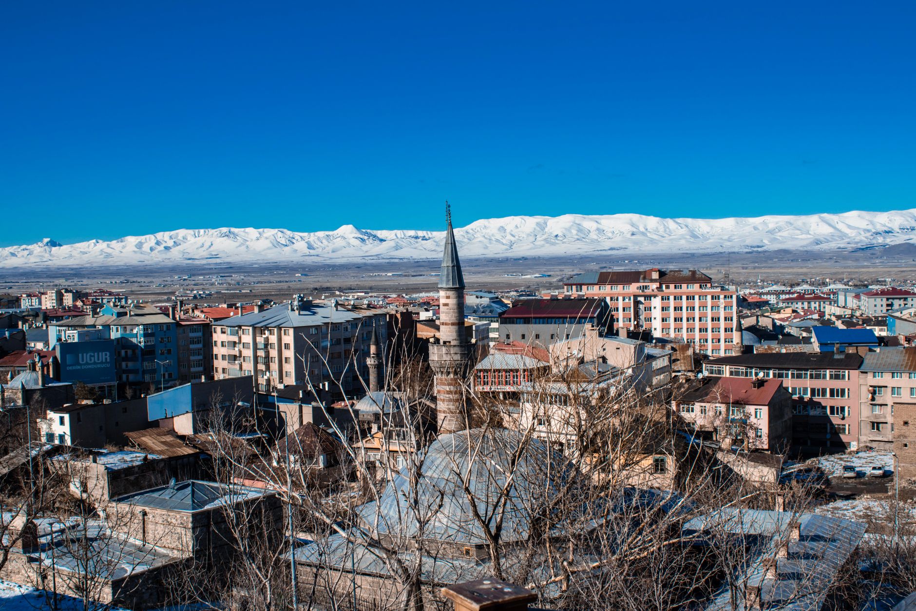 Aerial view of a mountain village with snowy peaks in the background.