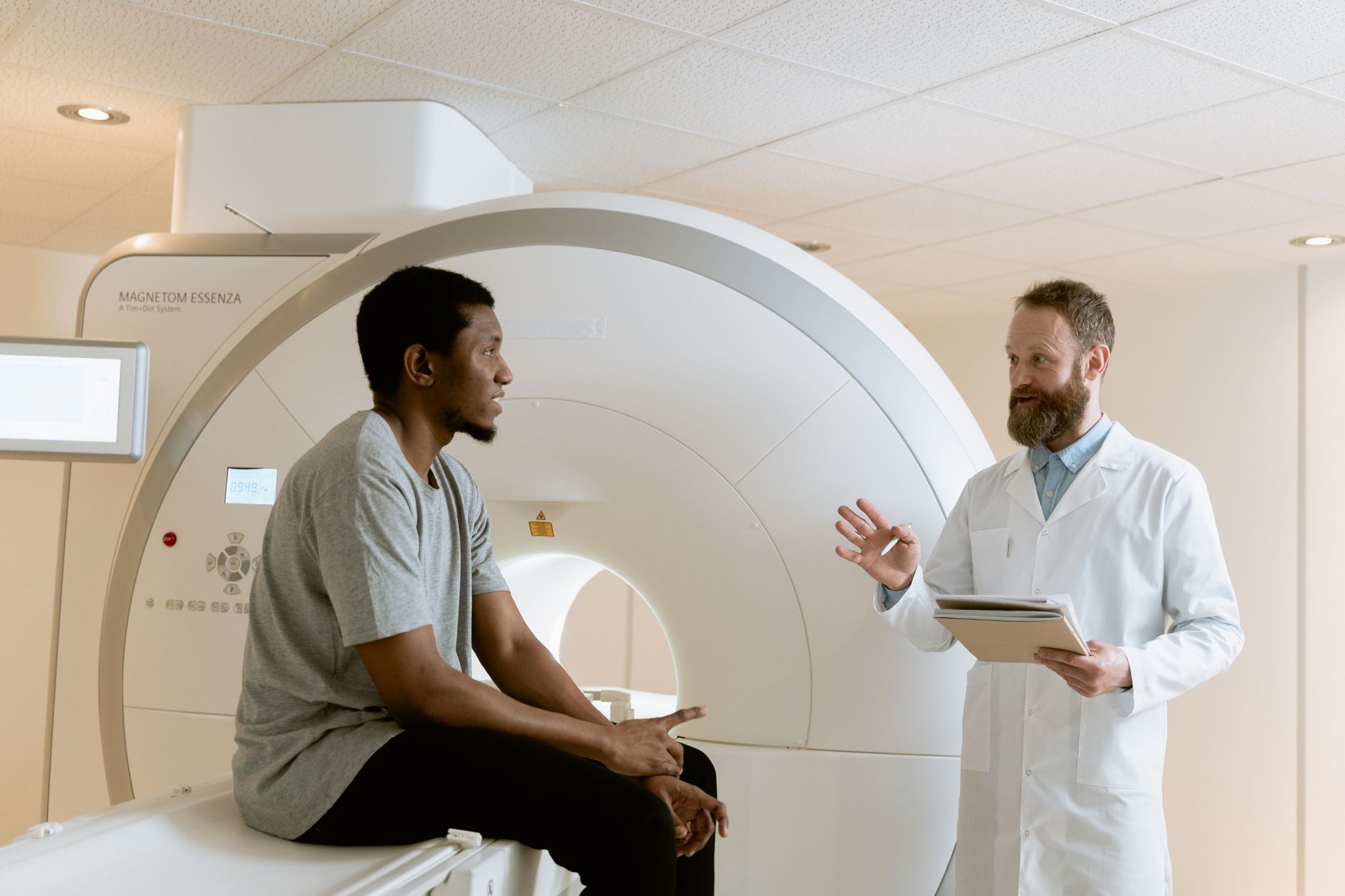 An oncologist explains the treatment plan to a patient in front of an MRI machine.